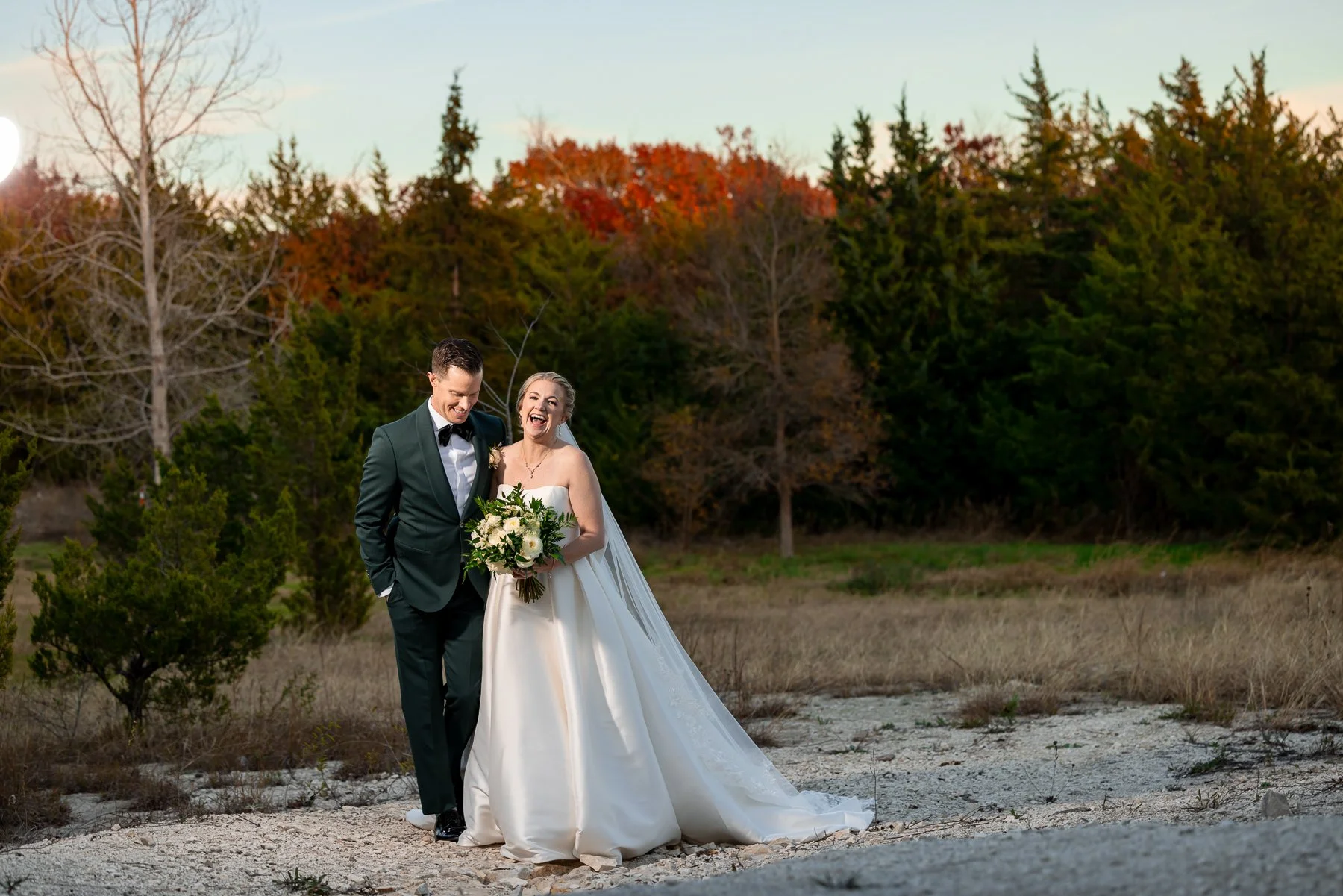 Bride and groom walking together through the natural surroundings at Stone Crest Venue near McKinney, TX.