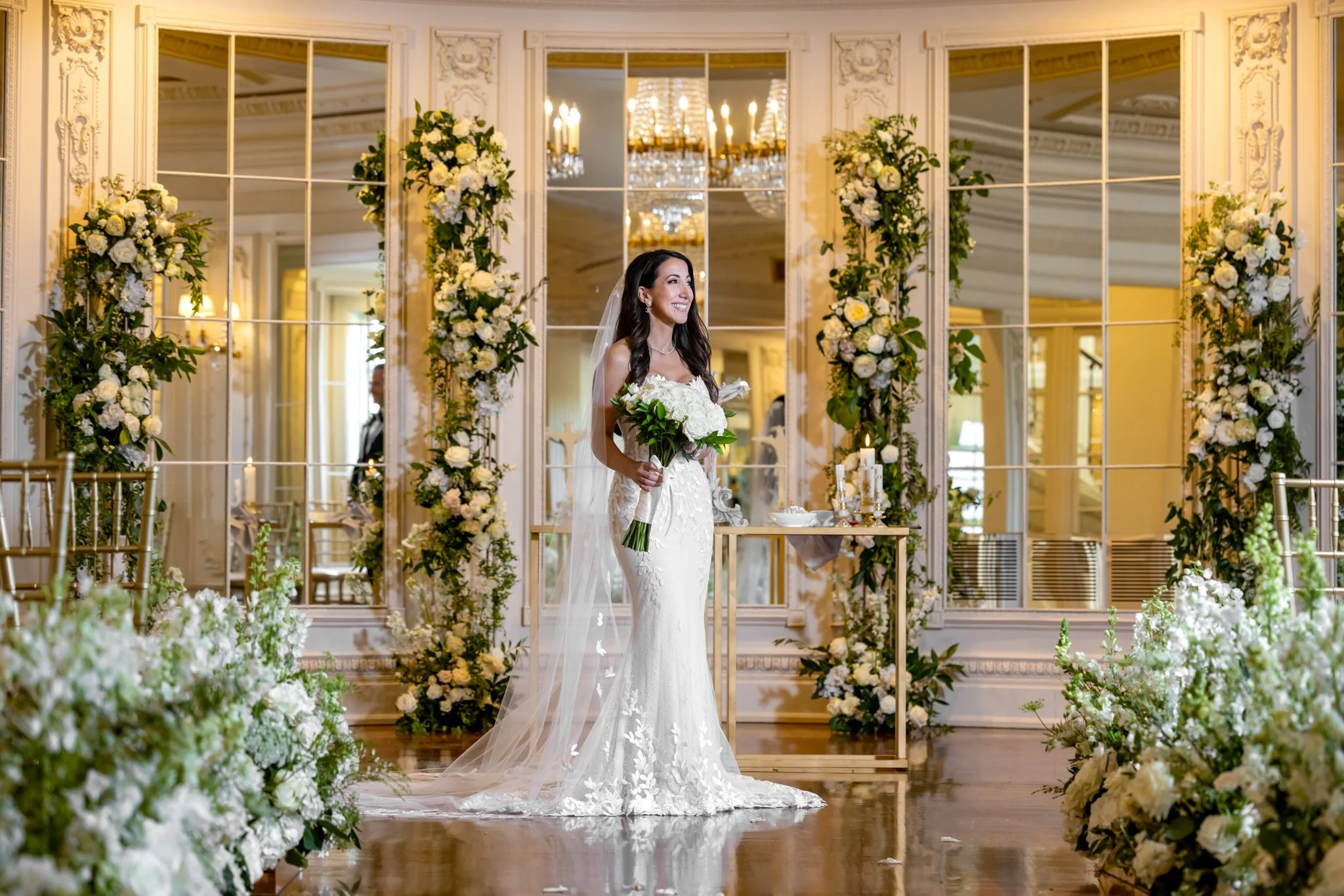 Bride holding a white and green wedding bouquet in an elegant wedding venue.