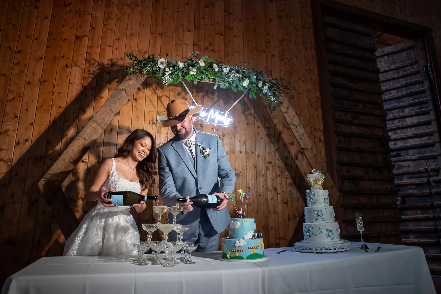 Bride and groom serving champagne beside their wedding cake at Lucky Spur Ranch in Justin, TX.