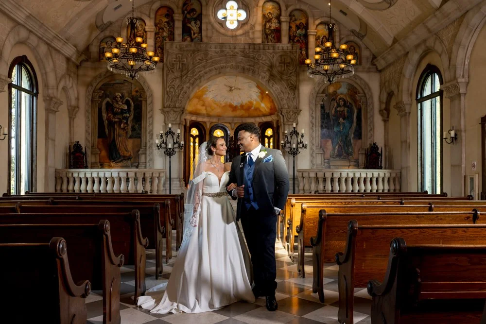 Wide portrait of Mallory and Marcus together in the chapel aisle.