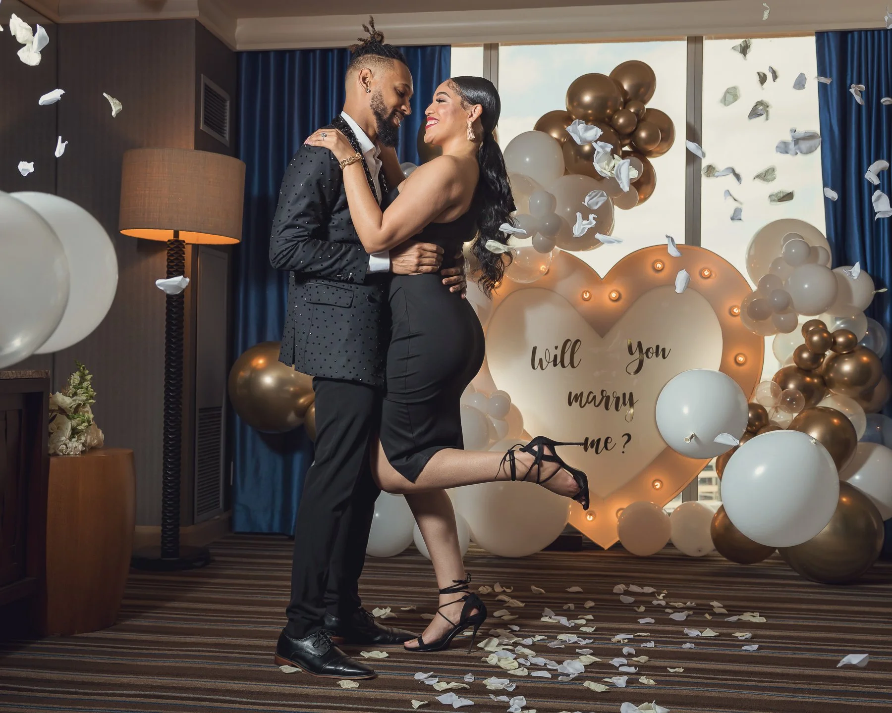 Newly engaged couple celebrating in front of a romantic surprise proposal setup in Dallas