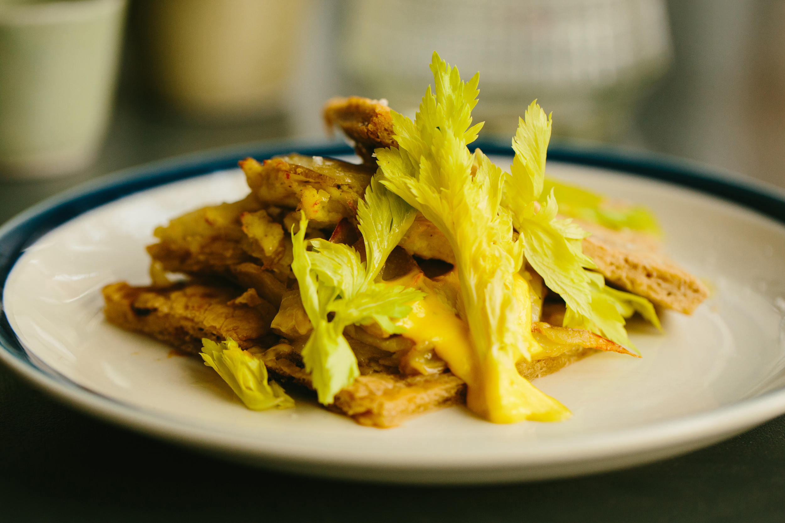 spanish tortilla on focaccia. cured black olive, saffron aioli, celery leaf