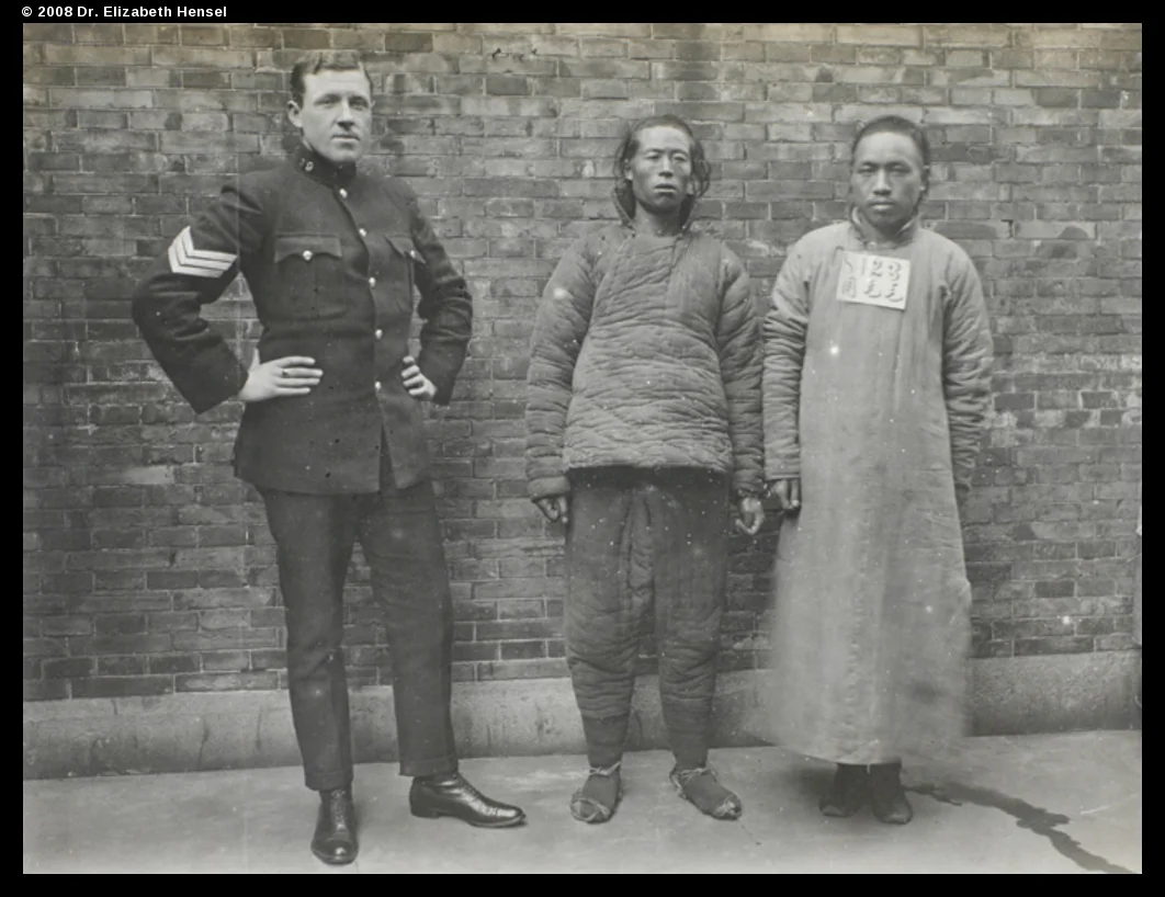 An SMP sergeant and two men. The sign on the left reads 'Hairy Zhou'. Zhou is the surname, I presume.