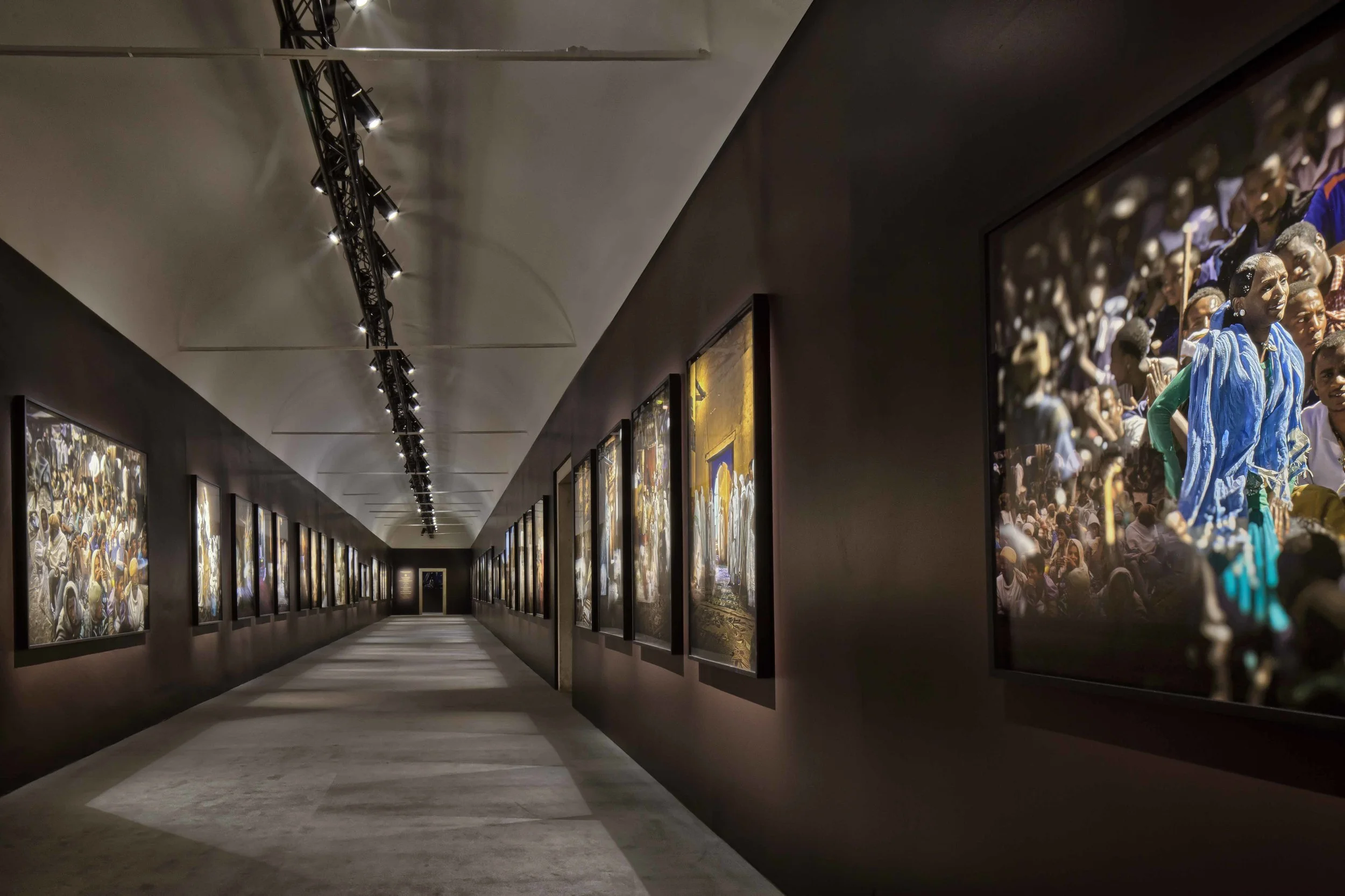 Mostra Fotografica Ethiopia Spiritual Imprints Abbazia di San Giorgio Maggiore, Venezia L’allestimento della mostra fotografica di Lizy Manola presso l’Officina del’Arte Spirituale nell’Isola di San Giorgio Maggiore, nasce da due obiettivi progettuali: armonizzare ogni foto con lo spazio, calibrando con cura lo sfondo che la incornicia; creare un’atmosfera suggestiva, capace di evocare la profonda spiritualità del popolo etiope. Una serie di interventi mirati hanno reso lo spazio essenziale, eliminando i dettagli superflui e razionalizzando il percorso fra gli ambienti. Si è rivelata così un’architettura pura, in cui opere diverse per intensità, luce e colore hanno trovato la loro giusta collocazione in cui un’accurata disposizione di luci e ombre, velate dal timbro terroso dello sfondo, esalta la viva suggestione del racconto fotografico. Data: 2014 Progettista: Paolo De Benedictis Collaboratori: Emina Gauzanovic, Maria Angilecchia Fotografa: Alessandra Chemollo << cambia progetto >>