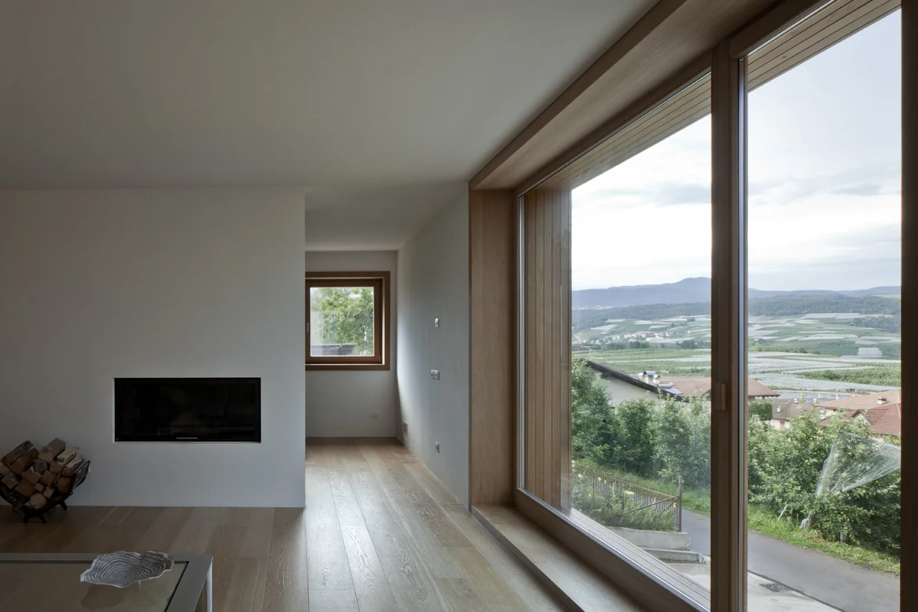 B&B Casa Incantata, Revò, Tn Tra i filari di mele della Val di Non, la demolizione e ricostruzione di un anonimo edificio residenziale degli anni '70 ha costituito l’occasione per recuperare il suo rapporto con il paesaggio e valorizzarne l’affaccio spettacolare sulla valle. La nuova architettura dal carattere formale estremamente semplificato, conserva proporzioni e volumetria originarie. Il linguaggio adottato reinterpreta i caratteri essenziali della tradizione alpina: corpo monolitico e compatto, intonaco bianco a finitura delle facciate, legno come naturale cornice delle aperture. Uniche eccezioni al vernacolo locale sono il contenimento della cornice di gronda all’interno delle murature perimetrali e la composizione libera delle aperture. I prospetti giocano, infatti, con la giustapposizione delle finestre, collocate in relazione ai diversi ambienti che sono chiamate a illuminare. La semplificazione dell’esterno dell’edificio si confronta con la ricchezza degli spazi interni, articolati attorno ad un monumentale vano scale. Collocato in posizione centrale, esso scandisce i diversi ambiti della casa attraverso rampe sovrapposte strette in un’intercapedine a doppia altezza. I tagli dei solai dilatano inaspettatamente lo spazio in senso verticale moltiplicando i traguardi visivi fra gli ambienti. Data: 2007 | 2011 Progettisti: Paolo De Benedictis, Glenda Flaim Progettista strutturale: Luca Pulignano Progettista impiantistico: Energytech G.m.b.H./S.r.l Fotografa: Alessandra Chemollo 2012 Premio di architettura città di Oderzo XIII edizione Progetto selezionato con menzione d’onore 2012 Selezione Nazionale RI.U.SO.01 2012. Rigenerazione Urbana Sostenibile Progetto Premiato 2013 Premio di architettura Costruire il Trentino 2009/2012 Progetto premiato ex aequo 2016 Rassegna Architetti Arco Alpino Casa Incantata - Progetto selezionato << cambia progetto >>