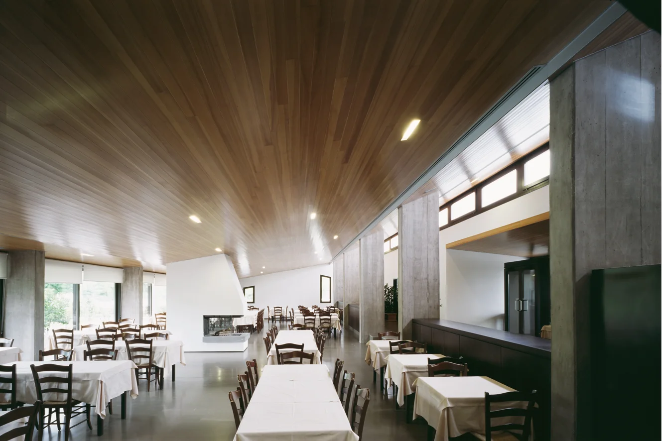 Ristorante Al Fogher, Camponogara, Ve L’edificio si trova su un’area rurale alla periferia di un piccolo centro vicino alla Riviera del Brenta, nei pressi di Dolo. Il progetto instaura con la campagna circostante un rapporto visivo e di dialogo attraverso il recupero e la reinterpretazione di elementi della tradizione: grandi logge finestrate, portici, tetti a falde. Due volumi di differente altezza, si addossano ad un terzo più alto posto sul retro. I due corpi in prossimità della strada, contengono, l’uno l’ingresso ed i servizi, l’altro la sala ristorante aperta a sud verso la campagna; il corpo sul fondo contiene le cucine e l’appartamento dei proprietari. La chiara organizzazione dei volumi si ritrova anche nell’organizzazione degli spazi interni. Data: 2000 | 2005 Progettisti: Paolo De Benedictis, Enrico Maria Raschi Progettista strutturale: Luca Pulignano Progettista impiantistico: Studio Vio Fotografa: Alessandra Chemollo << cambia progetto >>