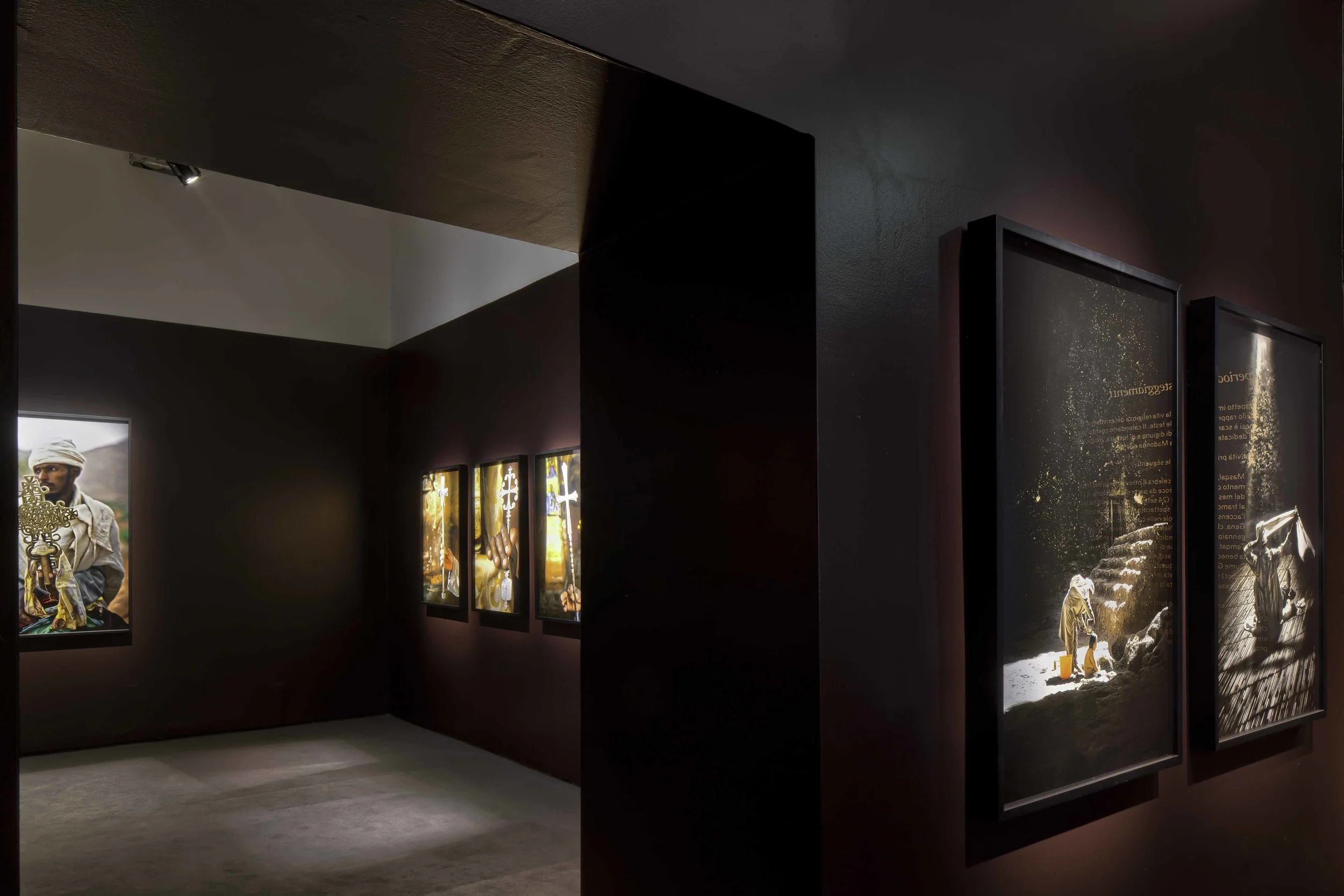 Photographic exhibition “Ethiopia Spiritual Imprints” Abbey of S. Giorgio Maggiore, Venice The set-up of Lizy Manola’s photo exhibition at the Officina del’Arte Spirituale on the San Giorgio Maggiore Island stems from two project objectives: to harmonize each photo with the surrounding space, carefully gauging the framing background; to create a suggestive atmosphere, able to evoke the deep spirituality of Ethiopian people. A number of ad hoc interventions have made space minimal, erasing reduntant details and rationalizing the way in between spaces. The result is a pure architecture, where photos of different intensity, light and colour have found their proper placement. A careful arrangement of light and shadow, veiled by the earthy tone of the background, intensify the profound fascination of the photographic narrative. Date: 2014 Architect: Paolo De Benedictis Assistants: Emina Gauzanovic, Maria Angilecchia Photography: Alessandra Chemollo << change project >> 