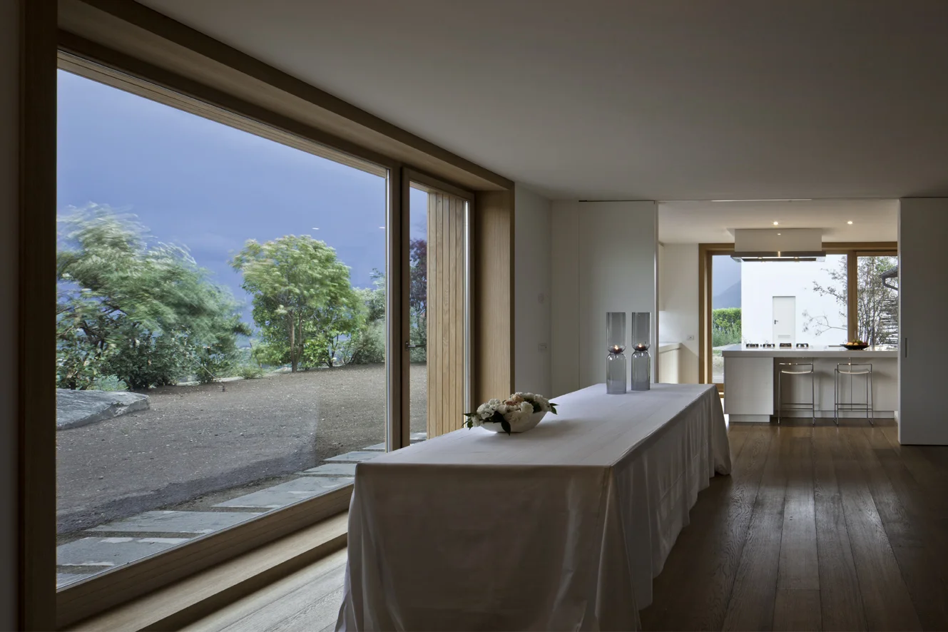B&B Casa Incantata, Revò, Tn Amongst the rows of apple trees in the Val di Non, the demolition and reconstruction of an anonymous 1970s residential building provided the opportunity to retrieve the building’s relationship with the landscape and value the spectacular view over the valley. The new, formal and extremely simplified architecture retains the original proportions and volumes. The project reinterprets the essential features of the alpine architectural tradition: monolithic and compact body, white plaster on the façades, and wood as natural frame for windows Exceptions to this local style are the embedding of the eaves within the perimeter walls and the free composition of the openings. The façades play with the juxtaposition of the windows, which are placed in relation to the different spaces that they are meant to light up. The simplification of the exterior of the building contrasts with the interior spatial complexity that is articulated around a monumental stairwell. Centrally located, the latter divides the various areas of the house through overlapping flights of stairs that are cast in a two-level gap between the walls. The cuts through the floor slabs unexpectedly open up the space vertically and multiplying the visual links between the rooms. Date: 2007 | 2011 Architects: Paolo De Benedictis, Glenda Flaim Structural Engineer: Luca Pulignano Services Engineer: Energytech G.m.b.H./S.r.l Photography: Alessandra Chemollo 2016 Prize Architetti Arco Alpino Selected project 2012 Oderzo City Architecture Prize XIII edition Selected Project with honorable mention 2012 National Selection RI.U.SO.01 2012. Sustainable Urban Rigeneration First prize-winning project 2013 Building Trentino Architecture Prize 2009/2012 Ex aequo prize-winning project << change project >>