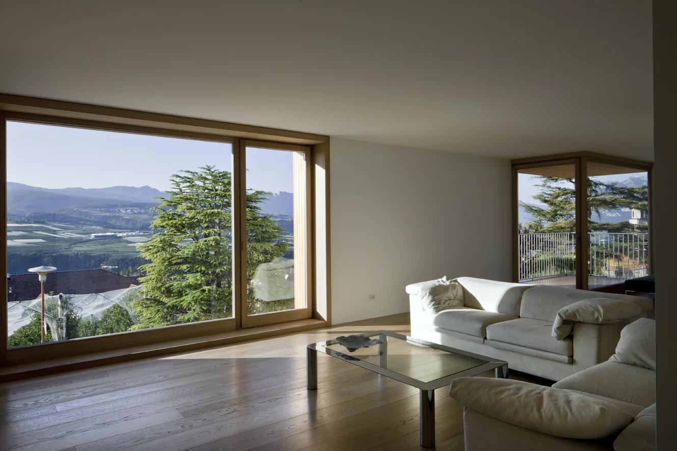 B&B Casa Incantata, Revò, Tn Amongst the rows of apple trees in the Val di Non, the demolition and reconstruction of an anonymous 1970s residential building provided the opportunity to retrieve the building’s relationship with the landscape and value the spectacular view over the valley. The new, formal and extremely simplified architecture retains the original proportions and volumes. The project reinterprets the essential features of the alpine architectural tradition: monolithic and compact body, white plaster on the façades, and wood as natural frame for windows Exceptions to this local style are the embedding of the eaves within the perimeter walls and the free composition of the openings. The façades play with the juxtaposition of the windows, which are placed in relation to the different spaces that they are meant to light up. The simplification of the exterior of the building contrasts with the interior spatial complexity that is articulated around a monumental stairwell. Centrally located, the latter divides the various areas of the house through overlapping flights of stairs that are cast in a two-level gap between the walls. The cuts through the floor slabs unexpectedly open up the space vertically and multiplying the visual links between the rooms. Date: 2007 | 2011 Architects: Paolo De Benedictis, Glenda Flaim Structural Engineer: Luca Pulignano Services Engineer: Energytech G.m.b.H./S.r.l Photography: Alessandra Chemollo 2012 Oderzo City Architecture Prize XIII edition Selected Project with honorable mention 2012 National Selection RI.U.SO.01 2012. Sustainable Urban Rigeneration First prize-winning project 2013 Building Trentino Architecture Prize 2009/2012 Ex aequo prize-winning project 2016 Prize Architetti Arco Alpino Selected project << change project >>