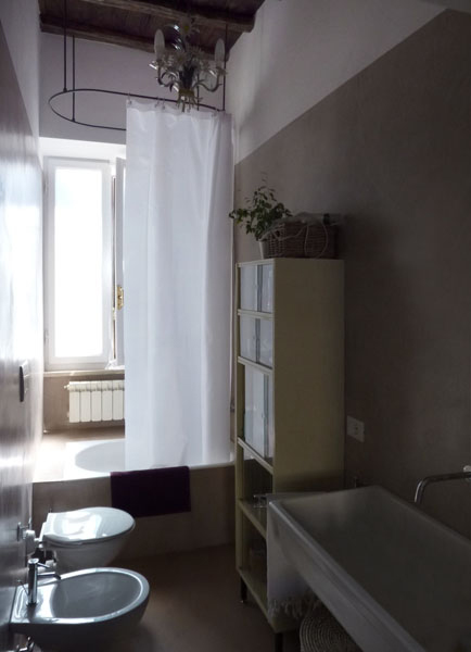 Il bagno, con il supporto per la tenda in metallo e la resina come rivestimento per pareti e pavimento