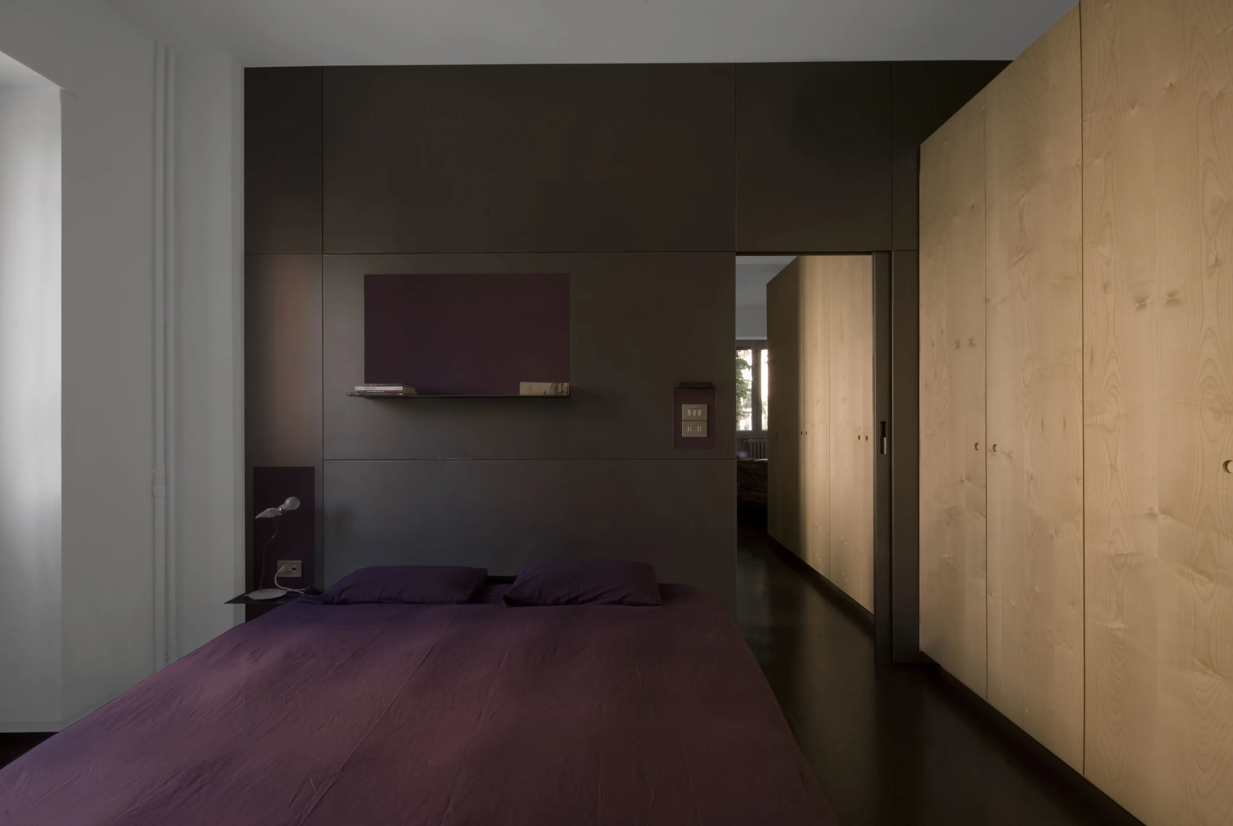 La camera da letto principale, con la parete in metallo a fare da testata del letto e il blocco degli armadi in legno sulla destra