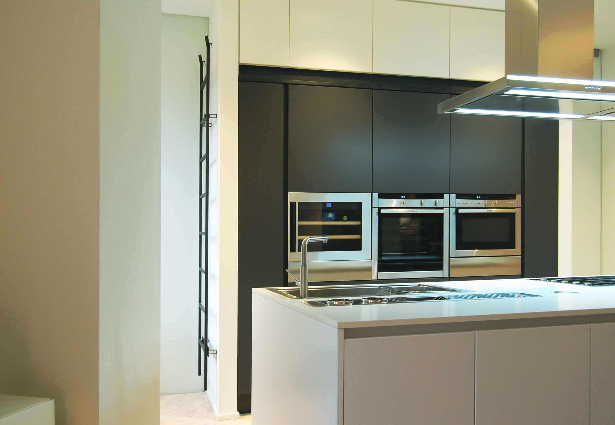 La cucina ad isola con alle spalle le colonne attrezzate. Una scala in metallo rimovibile consente l'utilizzo dei vani più alti.