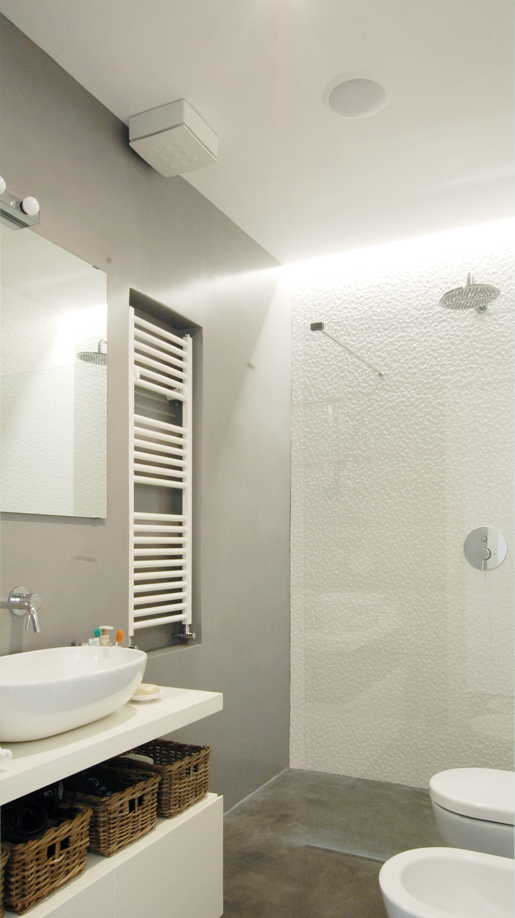 Il bagno, con la doccia a filo pavimento e la luce radente la parete.