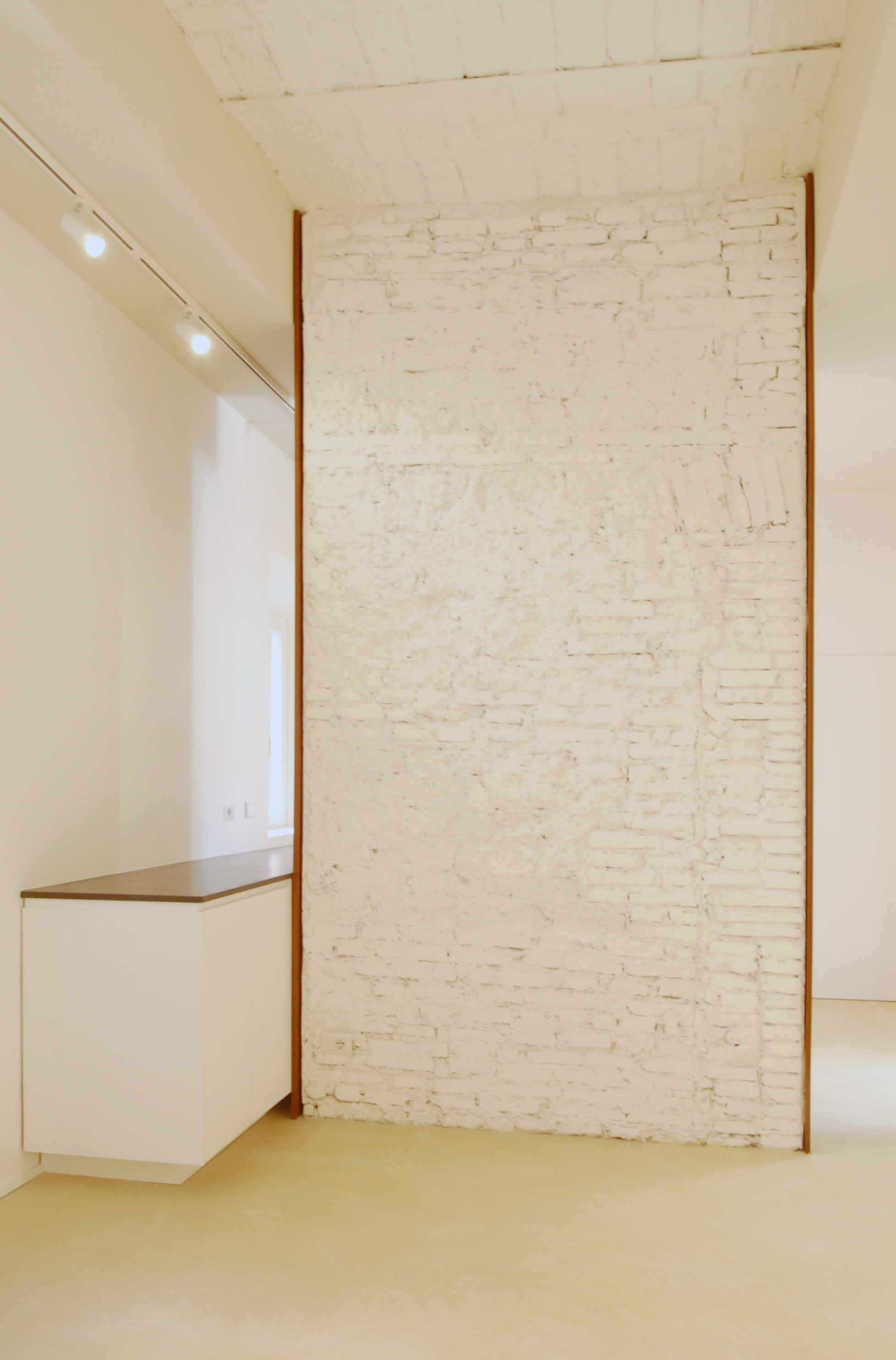 La visuale di entrata, con il setto in muratura a vista in primo piano a dividere la zona living dalla cucina. La sua larghezza misura anche la porzione di soffitto a voltine riportato alla luce.