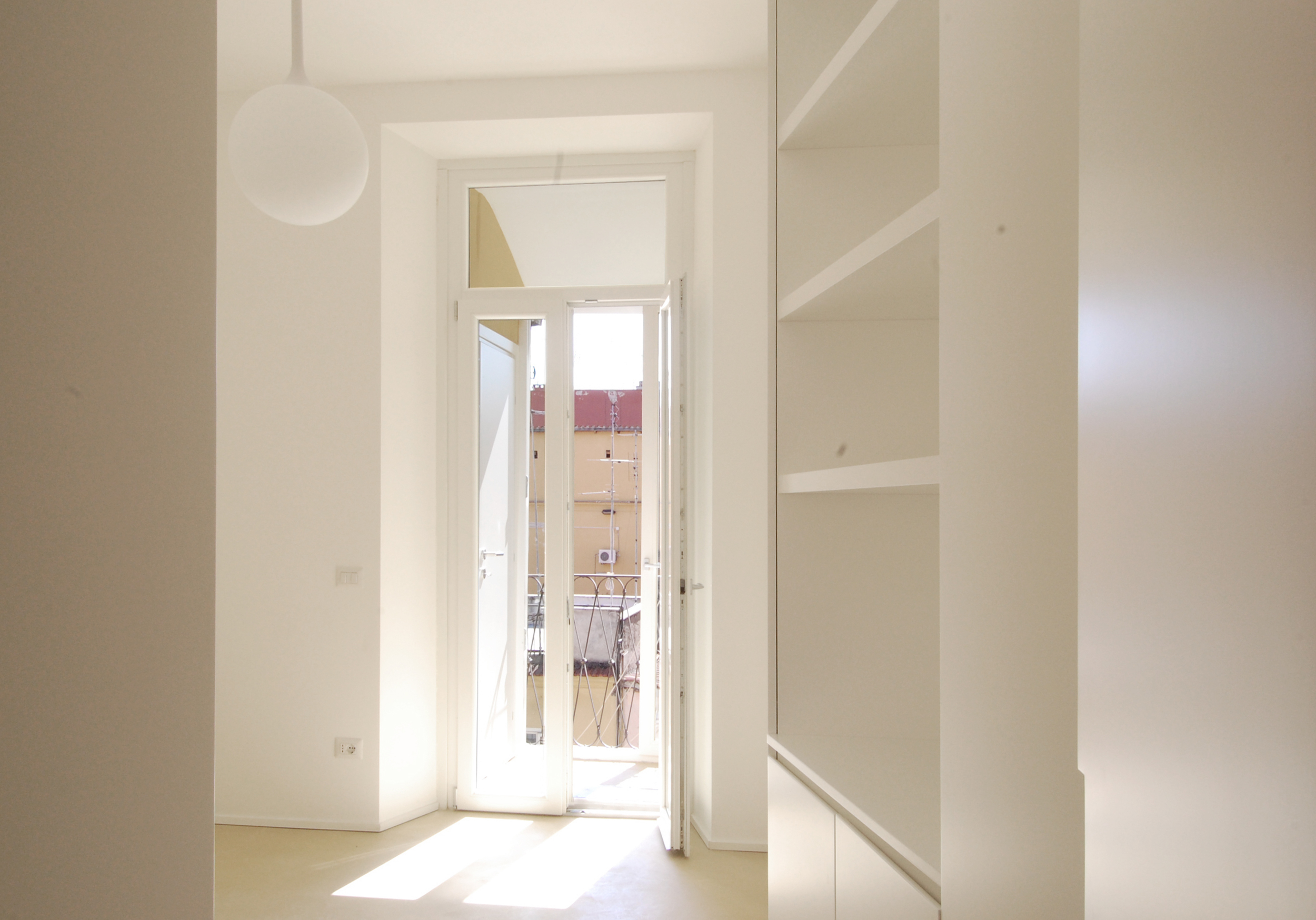 La camera da letto in uno scorcio d'entrata, con il balcone sullo sfodo.