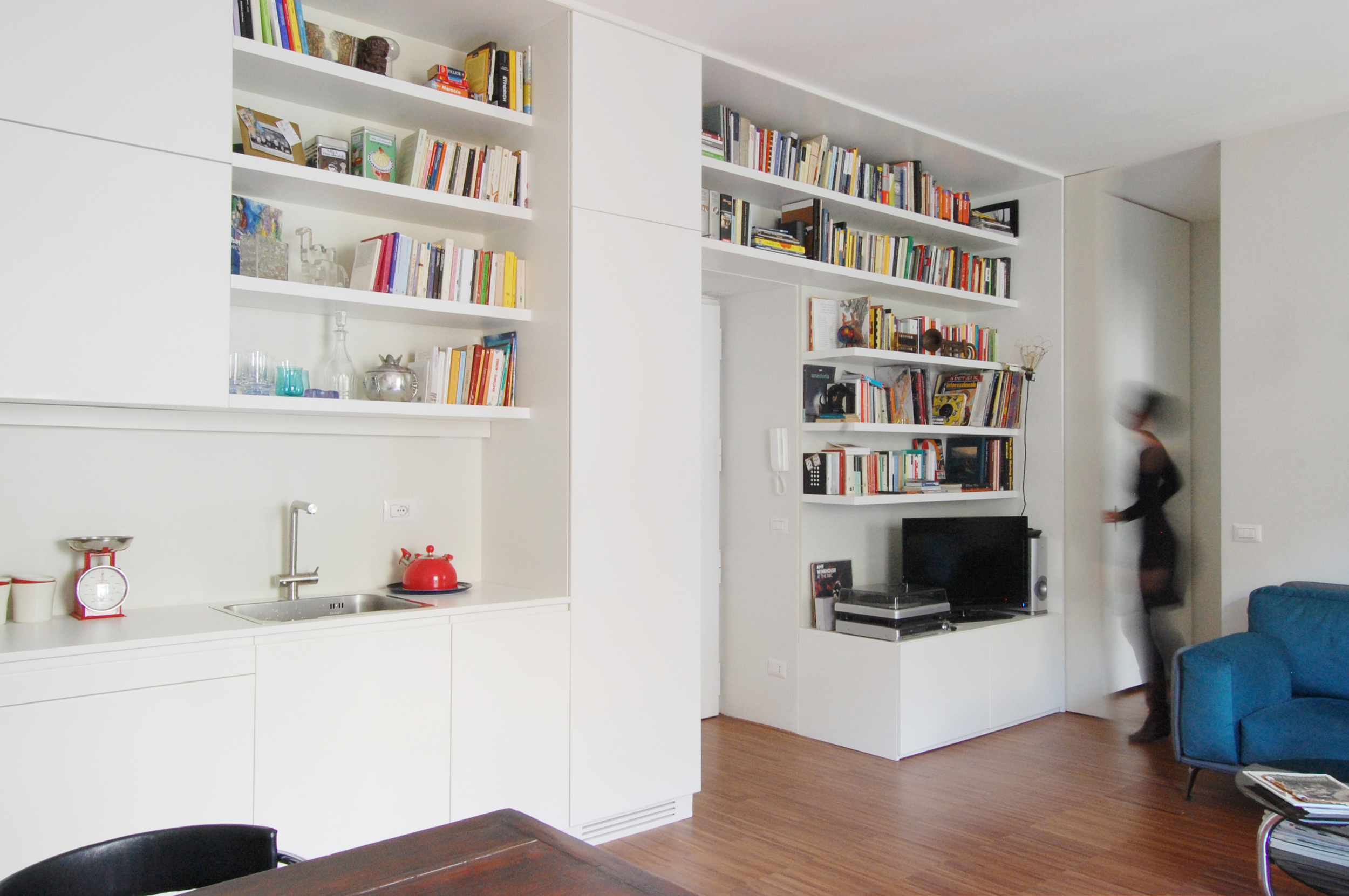 La parete attrezzata che attraversa tutta la casa, divenendo allo stesso tempo libreria, cucina, ripostiglio e armadio per la zona notte.