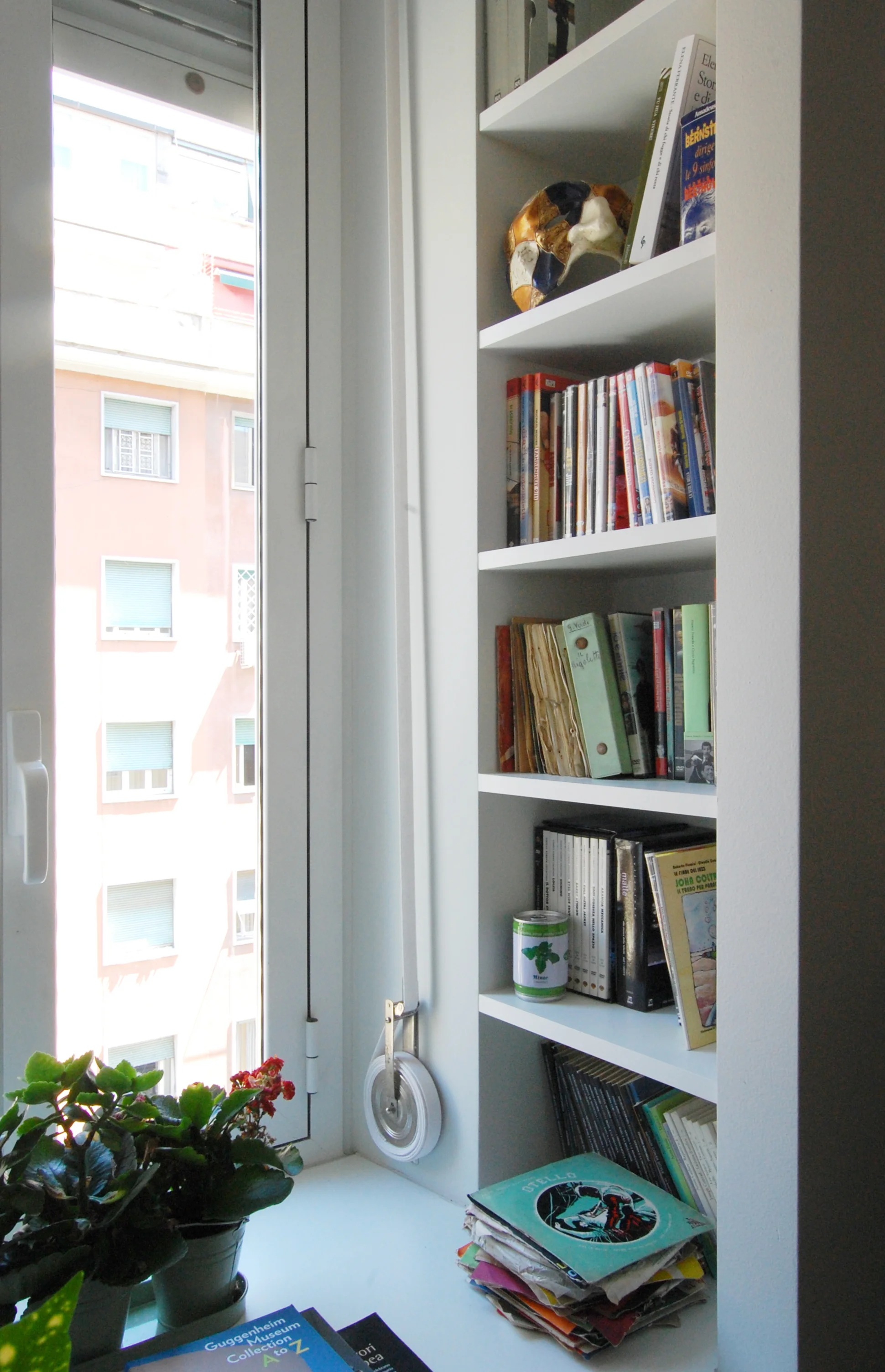 Libri e ricordi di viaggio animano una piccola libreria nella zona living, Ricavata accanto alla finestra, sfrutta una imperfezione nella geometria della muratura perimetrale.