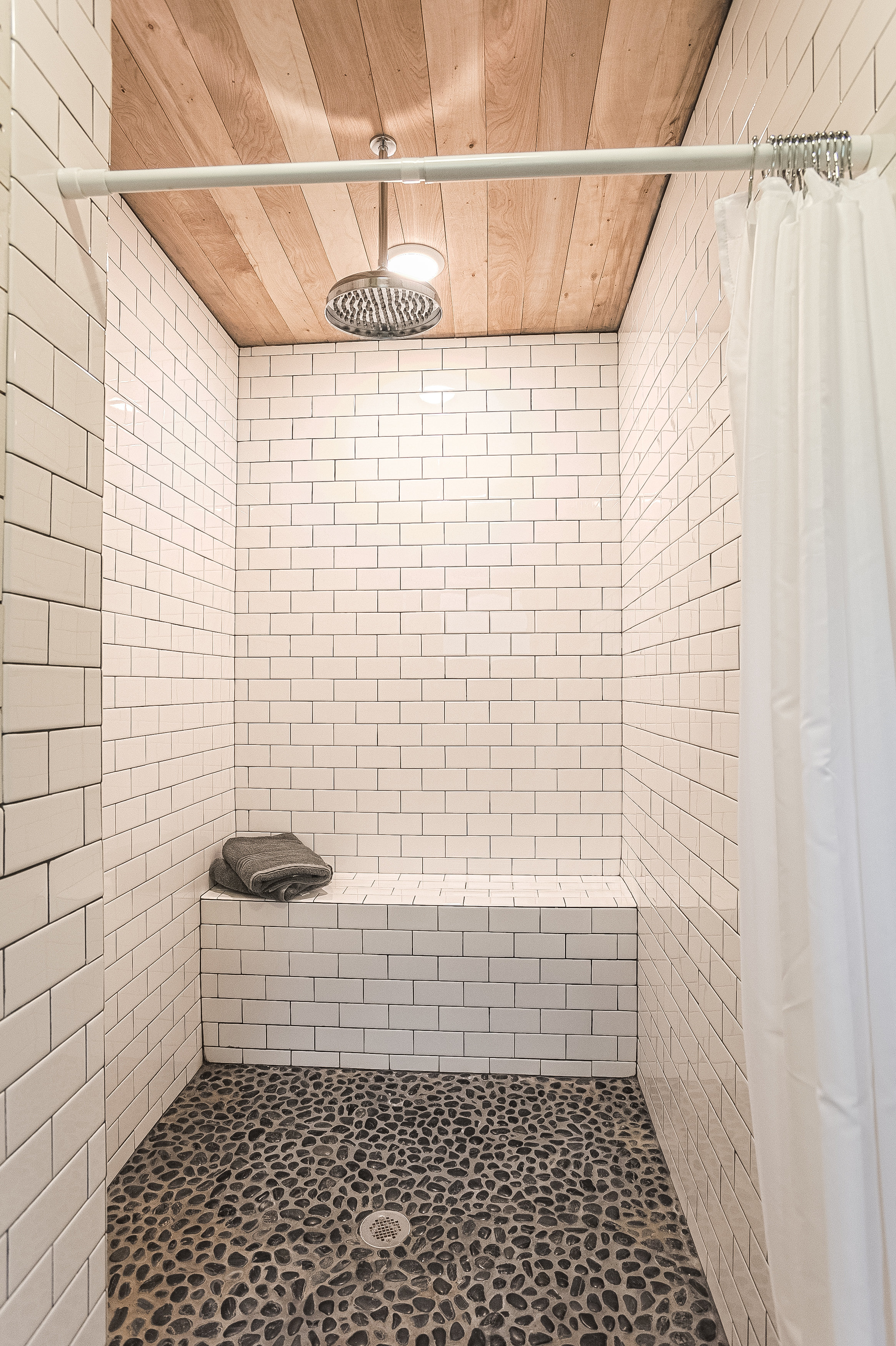 Subway tiled main house master bath with relaxing rain shower and river stones that massage your feet.