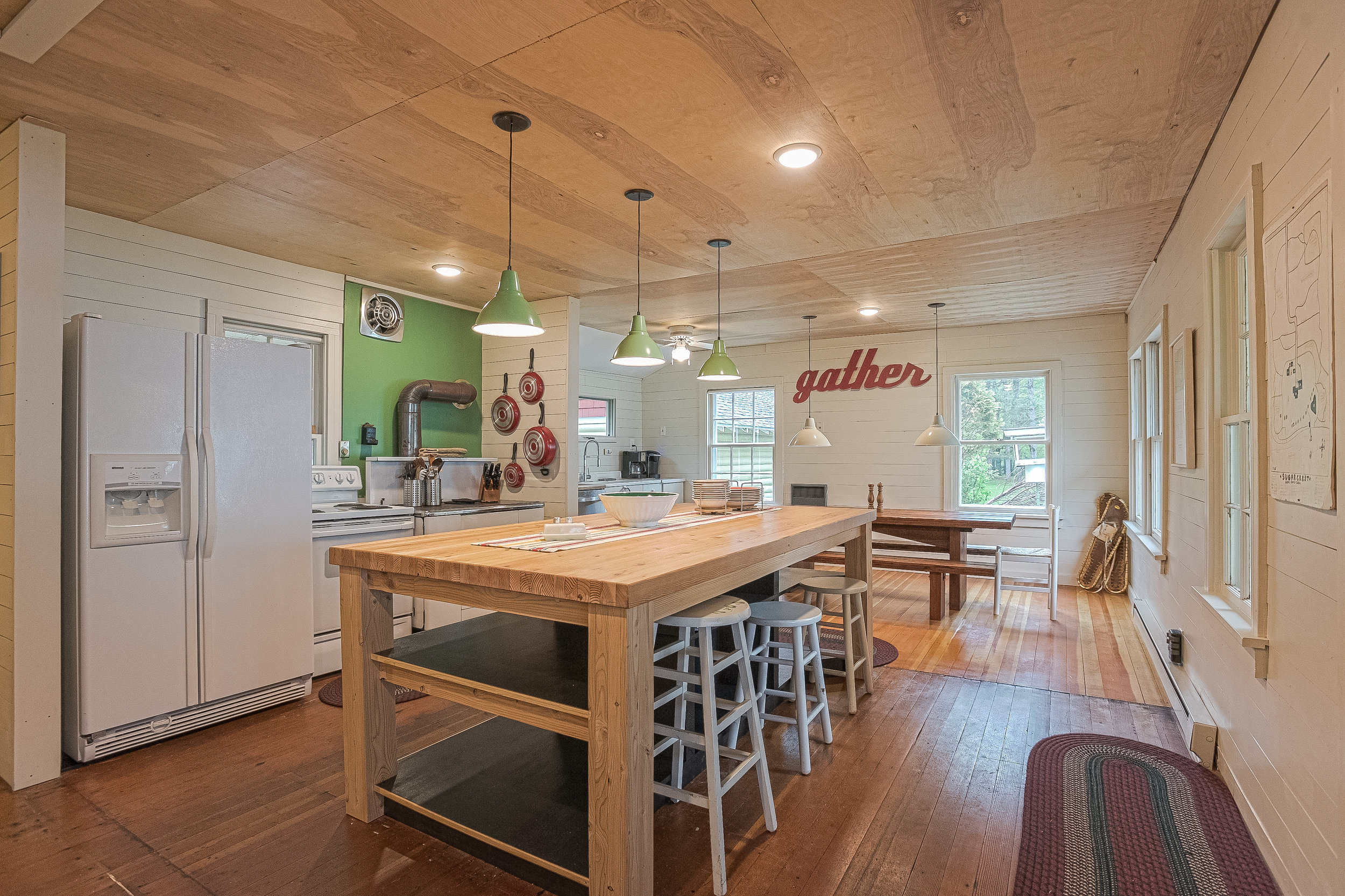 Retro kitchen open to living room with original hardwoods, big butcher block island for staging with plenty of storage and a long dining table for group meals.