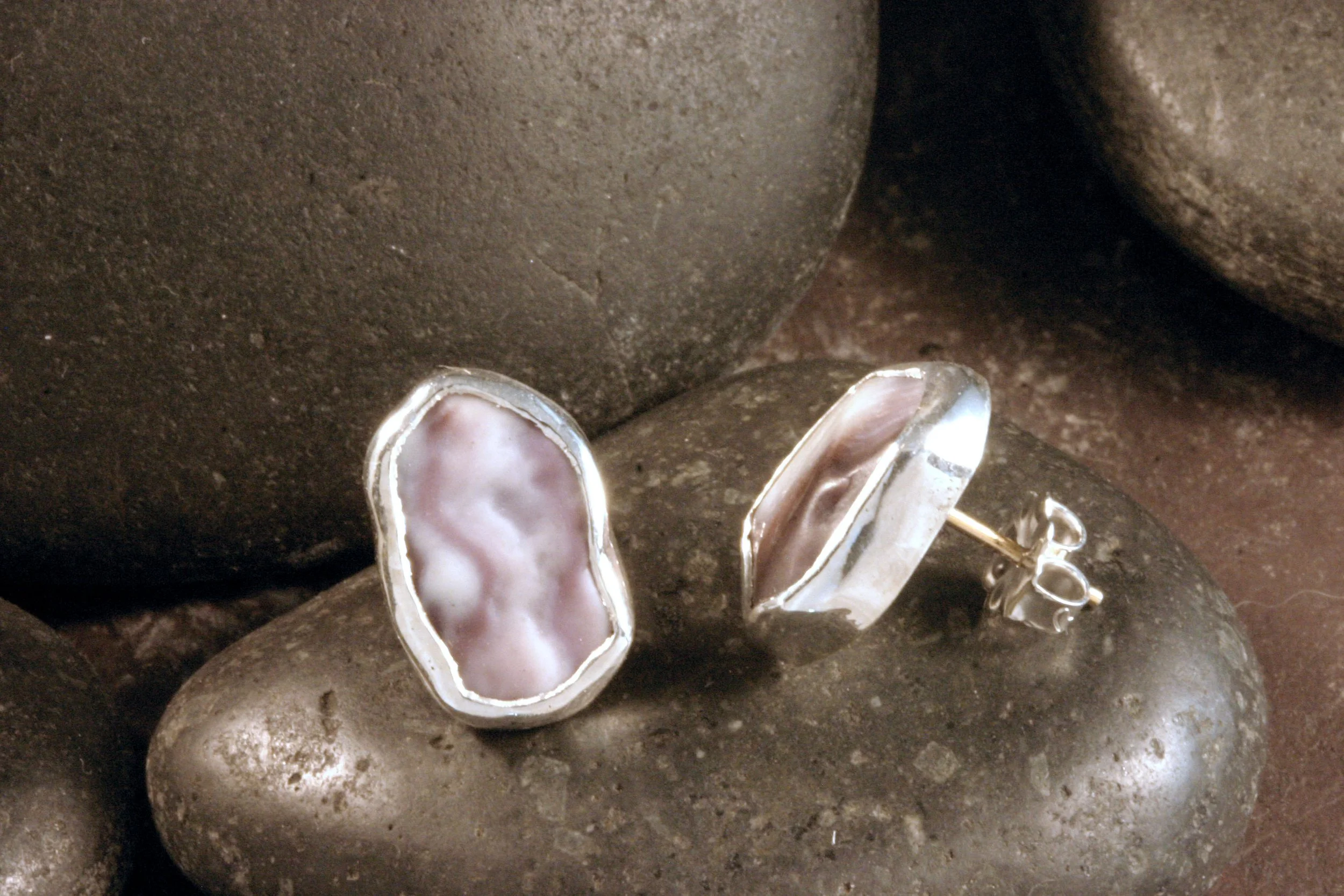 A side view of small sterling silver freeform pentagon wampum stud earrings.