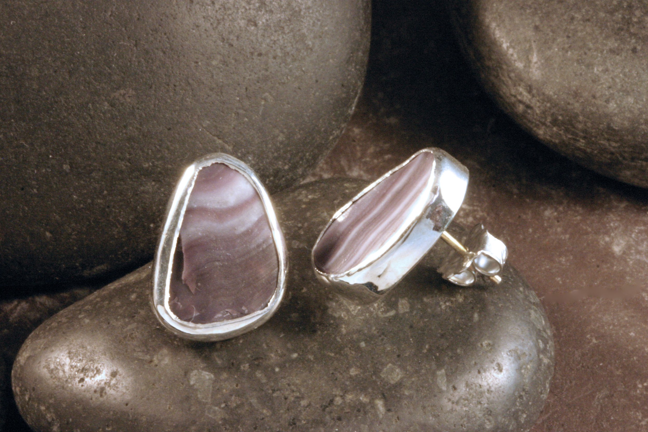 A side view of small sterling silver triangle wampum stud earrings.