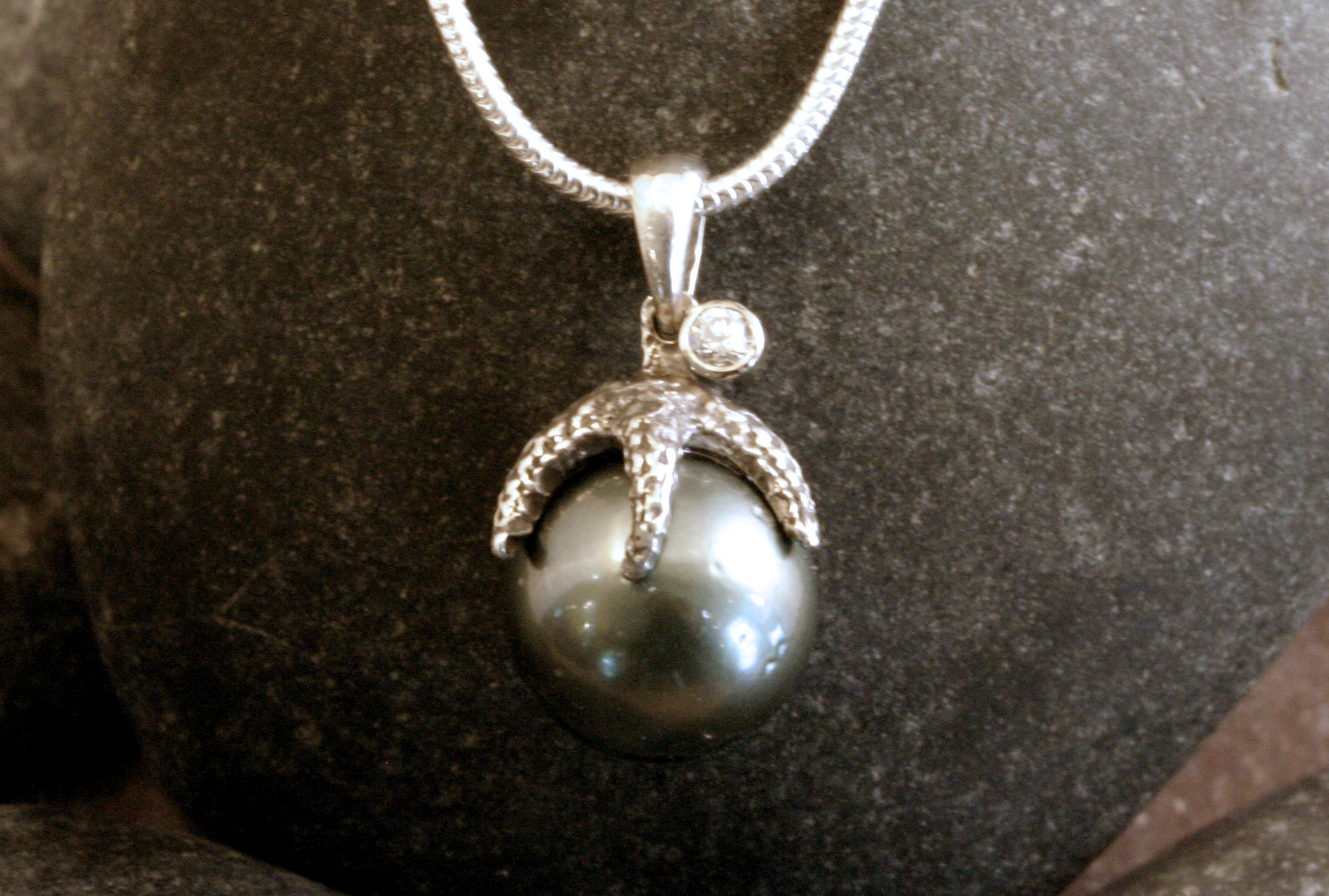 A sterling silver Tahitian pearl, diamond, & starfish pendant.