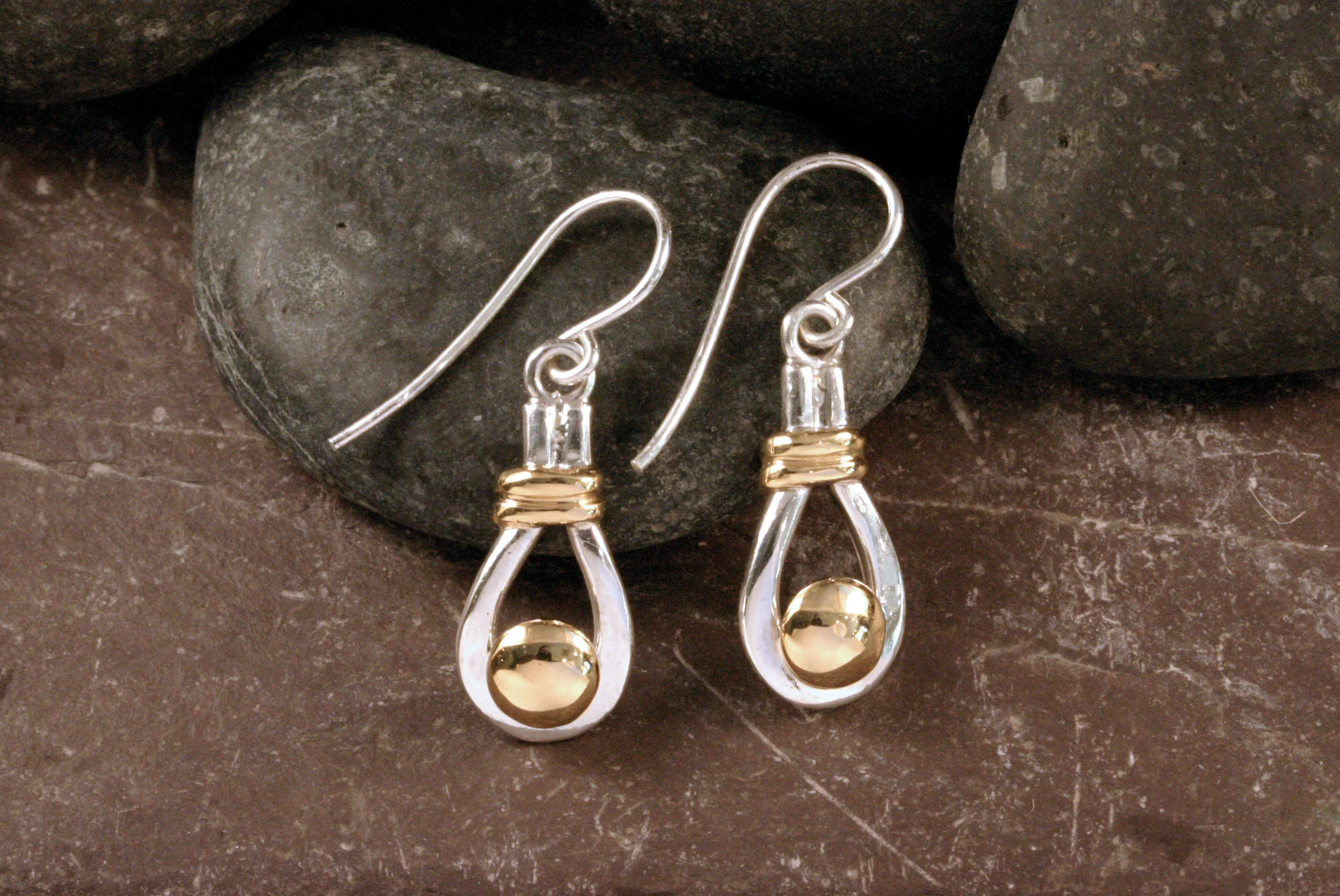 Sterling silver and 14K gold button dangle earrings on rocks.