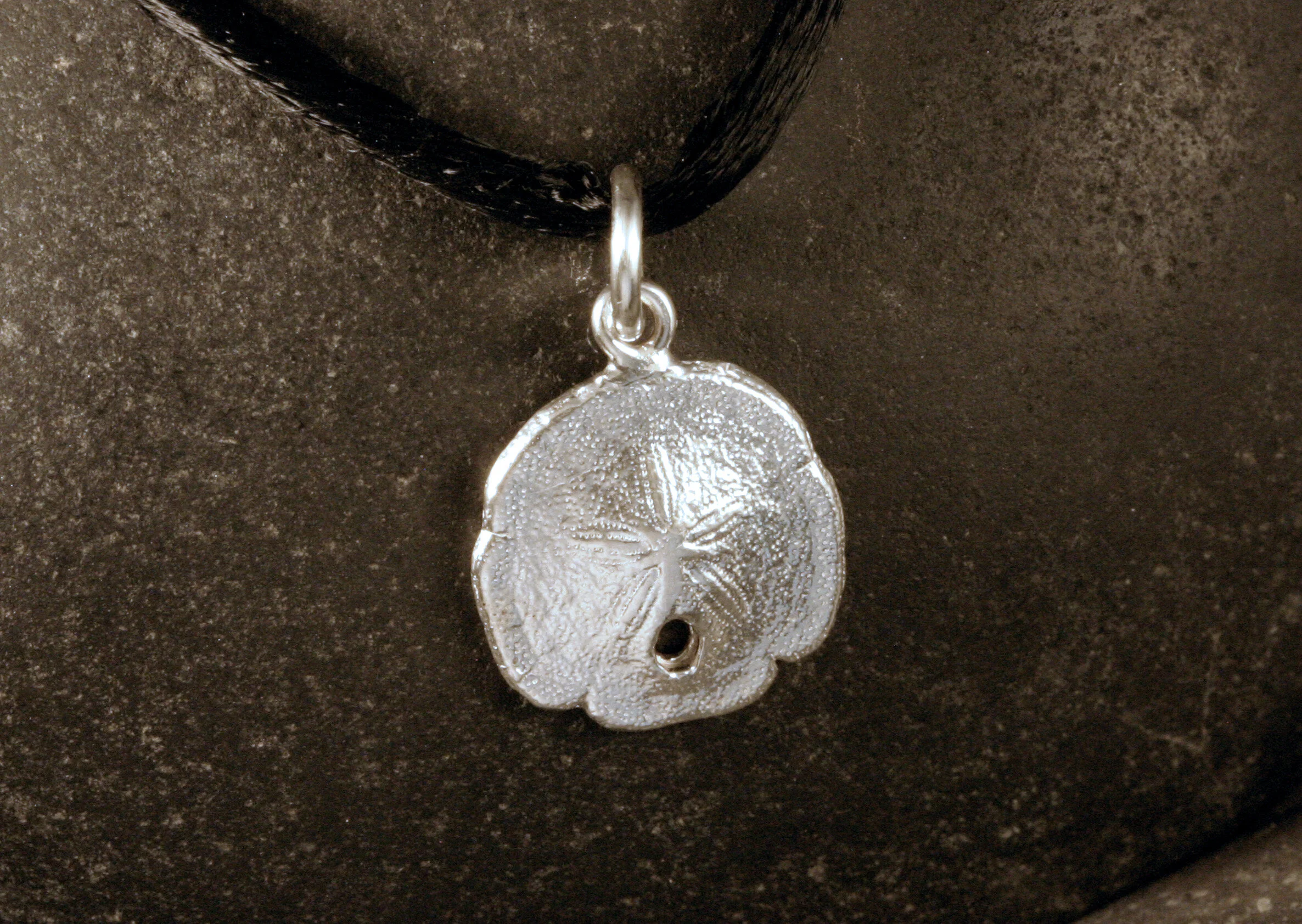 A small sterling silver sanddollar charm