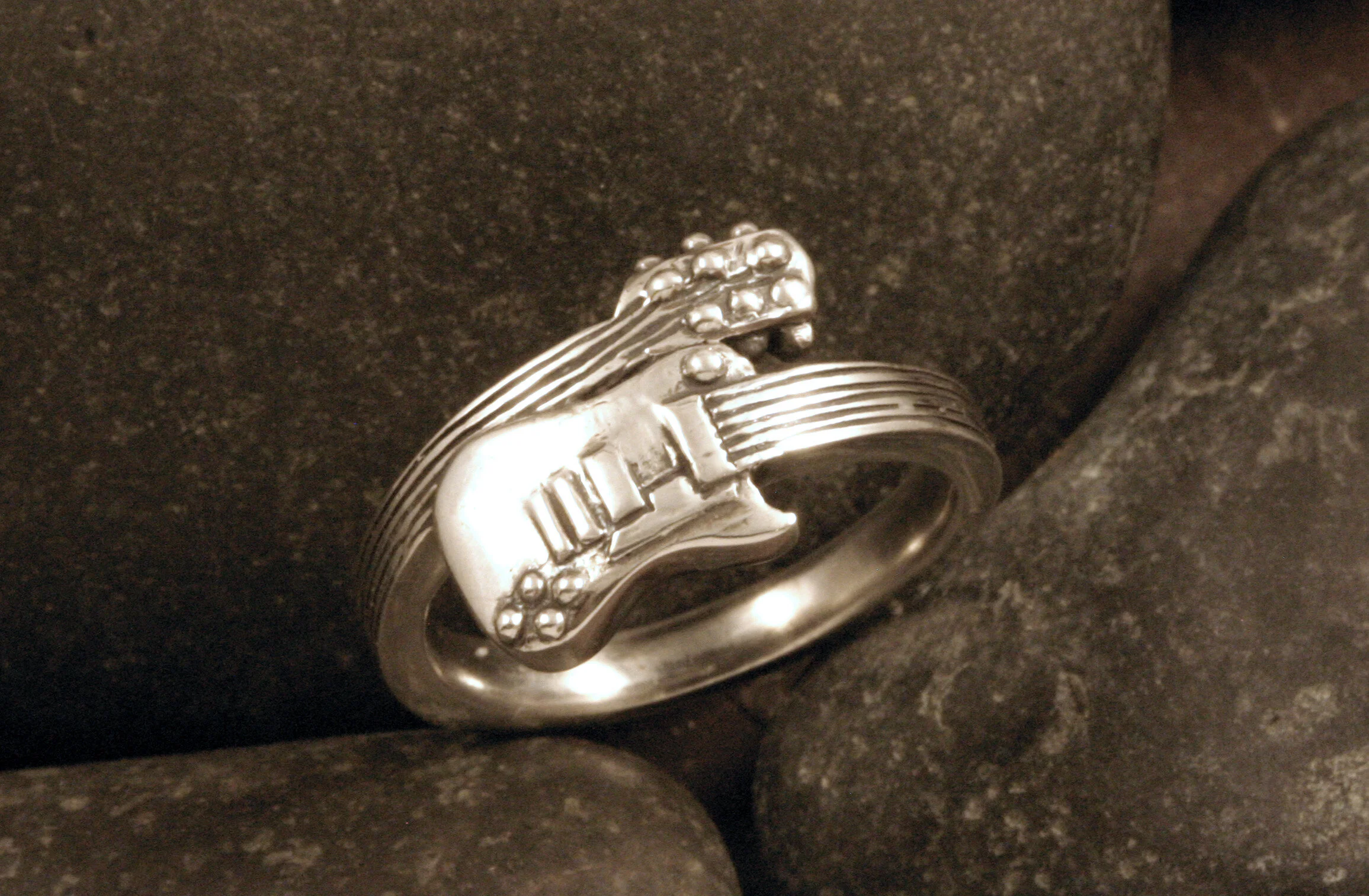 Small oxidized sterling silver guitar ring angled view.