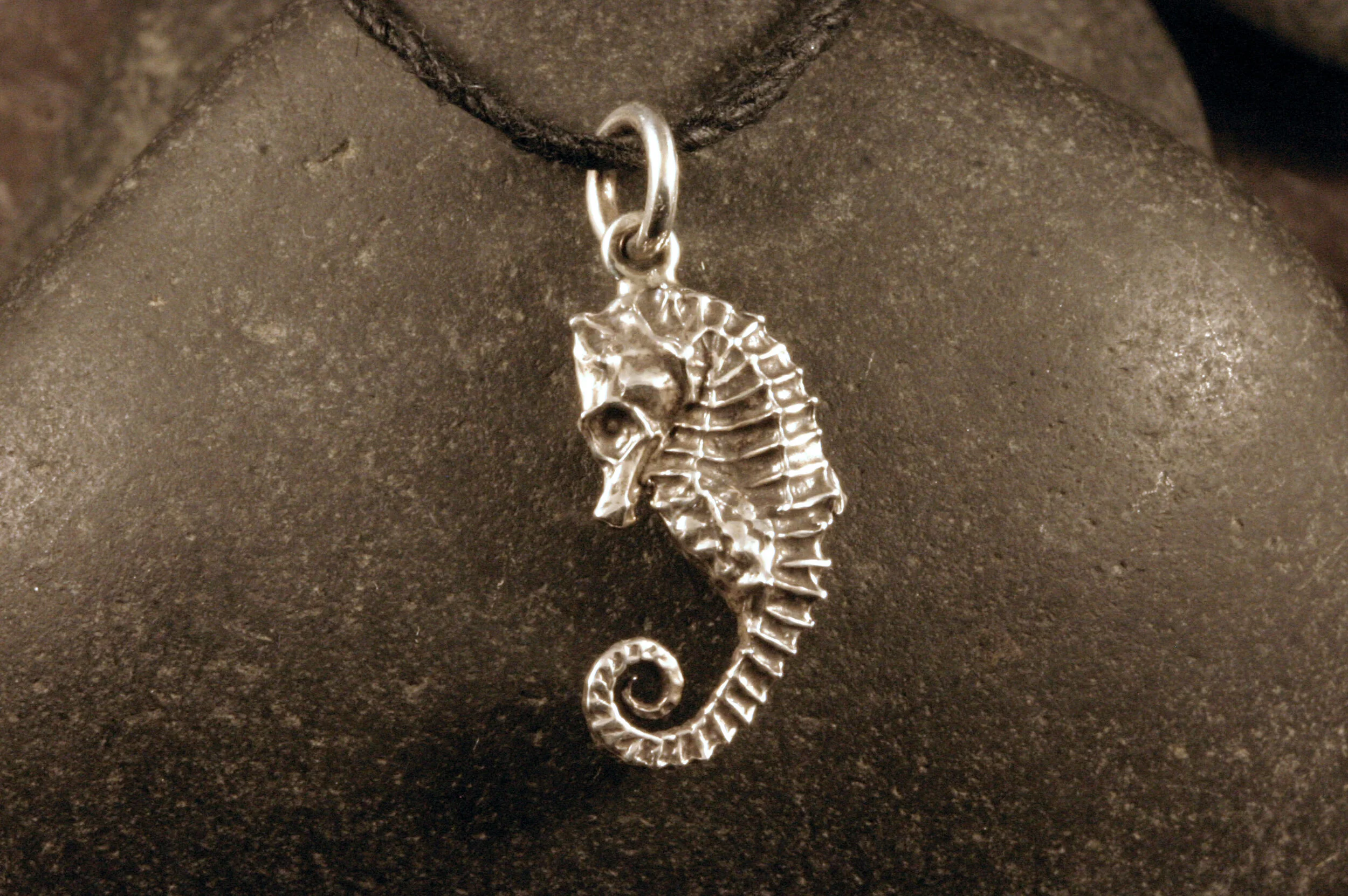 Left side view of oxidized sterling silver seahorse with curled tail charm.