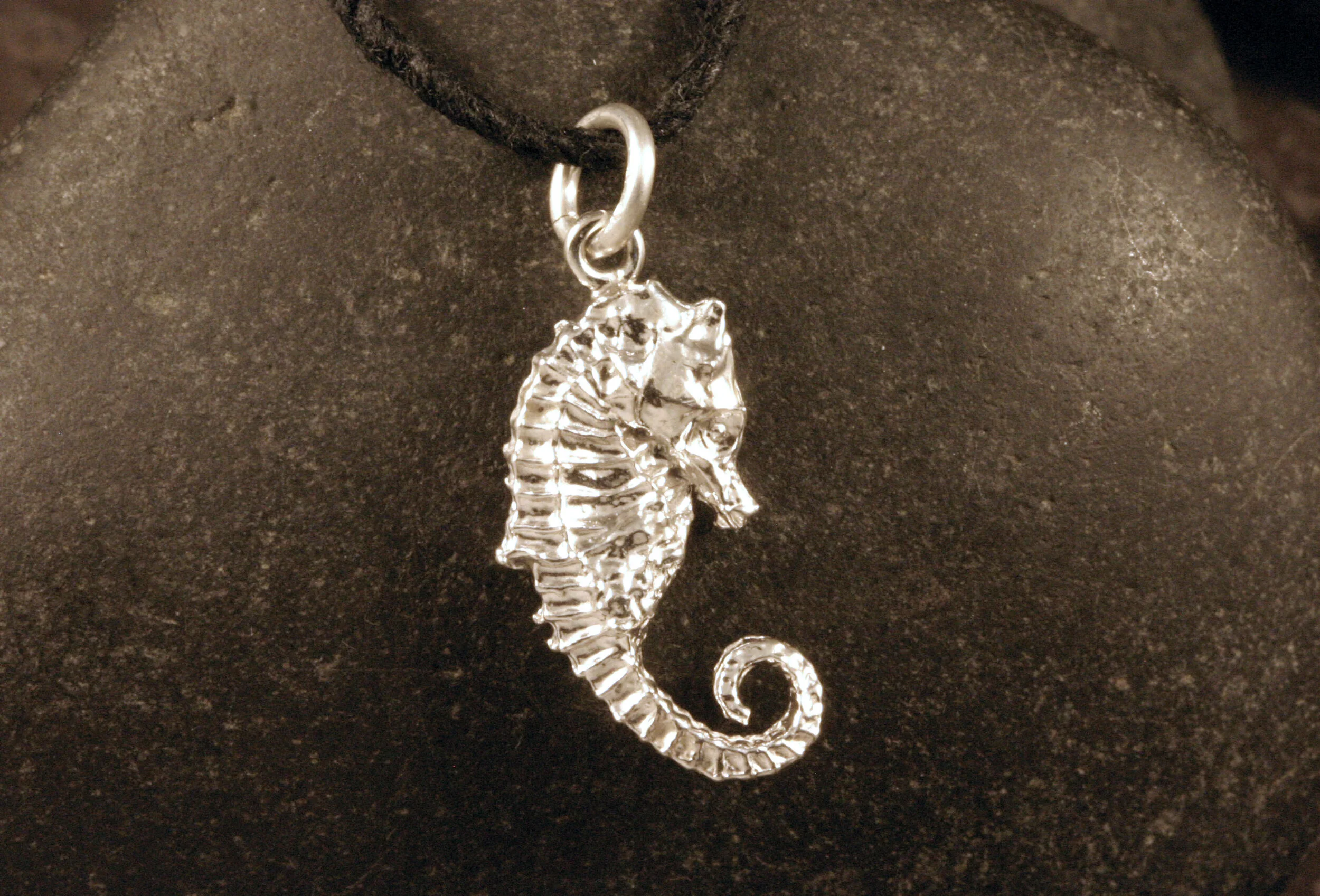 Right side view of shiny sterling silver seahorse with curled tail charm.