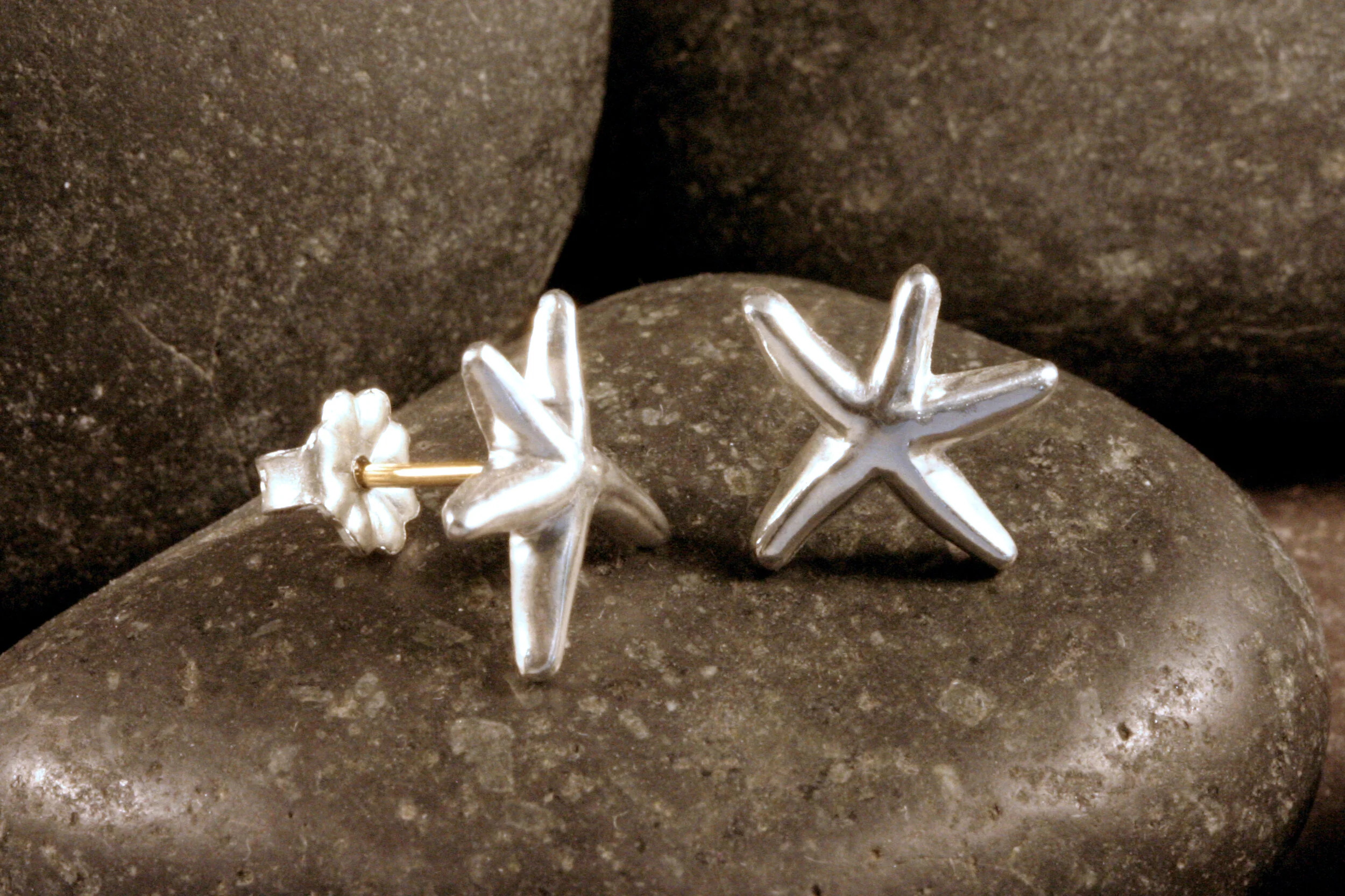 Small sterling silver smooth dancing starfish stud earrings with 14K gold posts in a side view.
