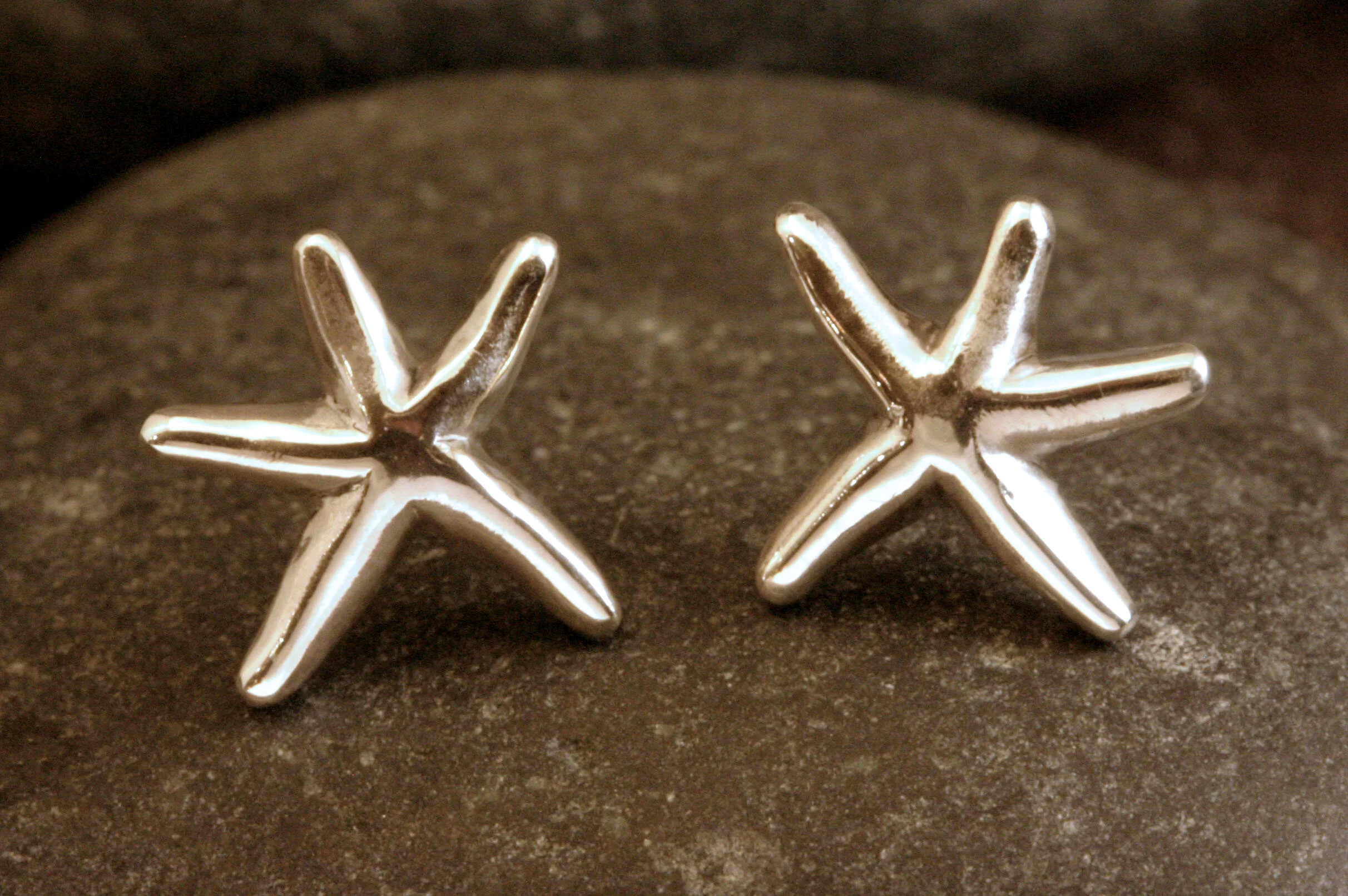 Small sterling silver smooth dancing starfish studs in a front view.