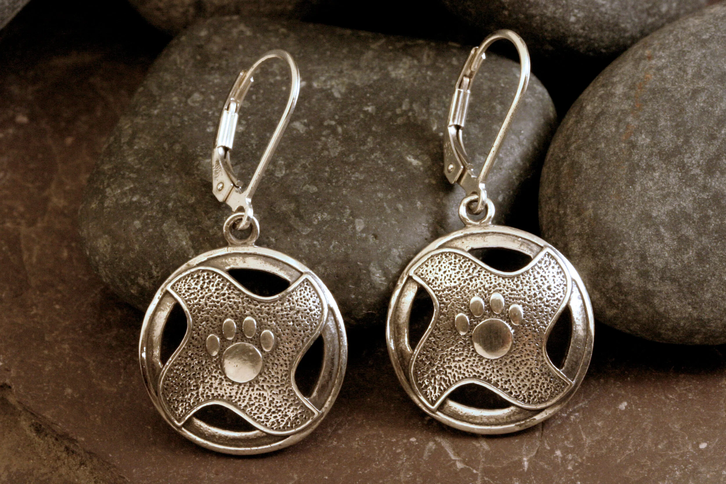 Oxidized sterling silver dangle earrings with pawprints in the center of a geometric design.