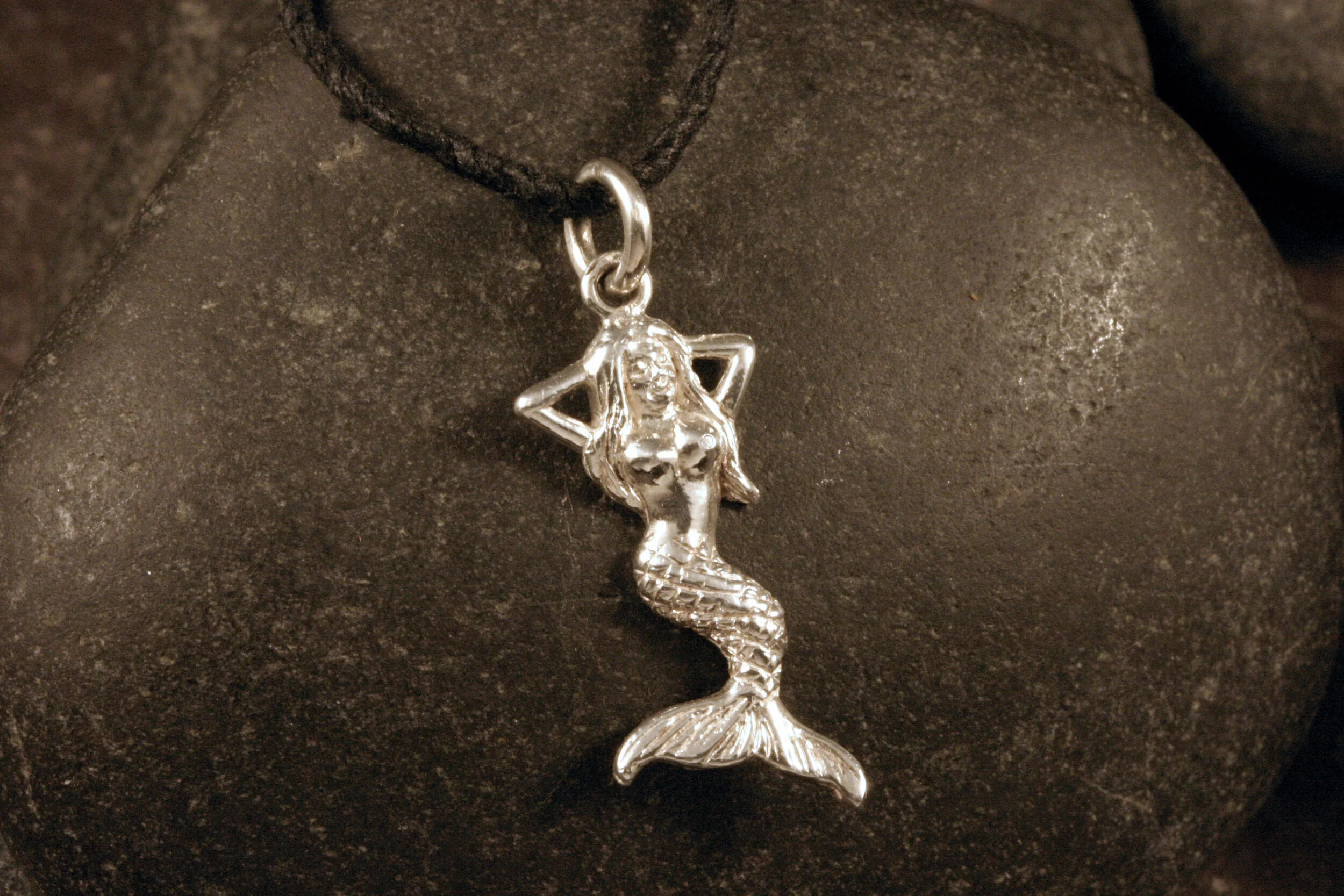 A shiny sterling silver mermaid charm.