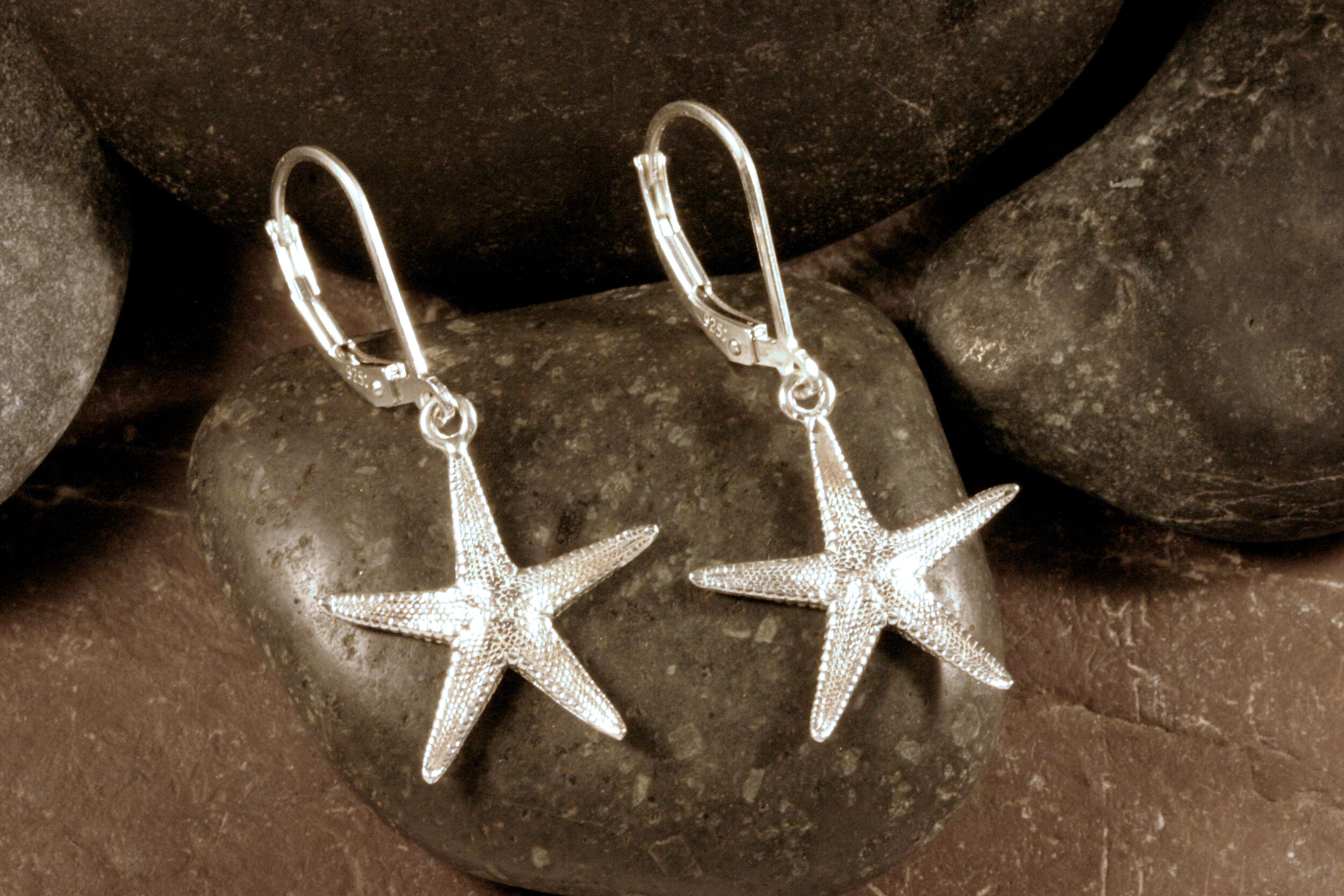 Shiny sterling silver sugar starfish dangle earrings.