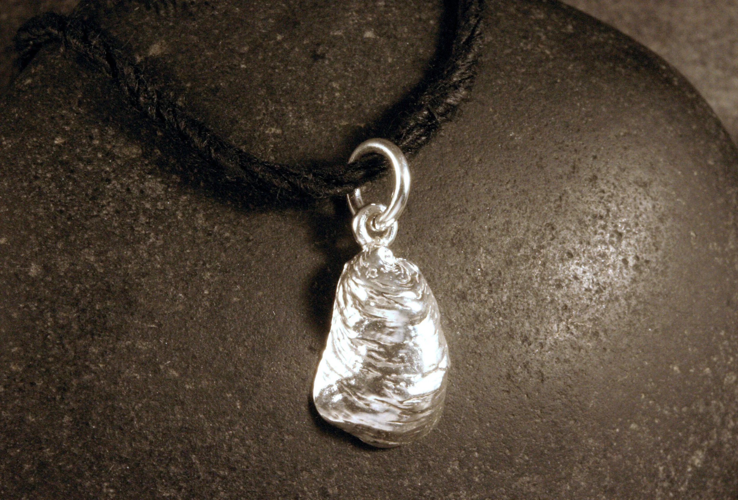 A shiny sterling silver mini oyster seashell charm.