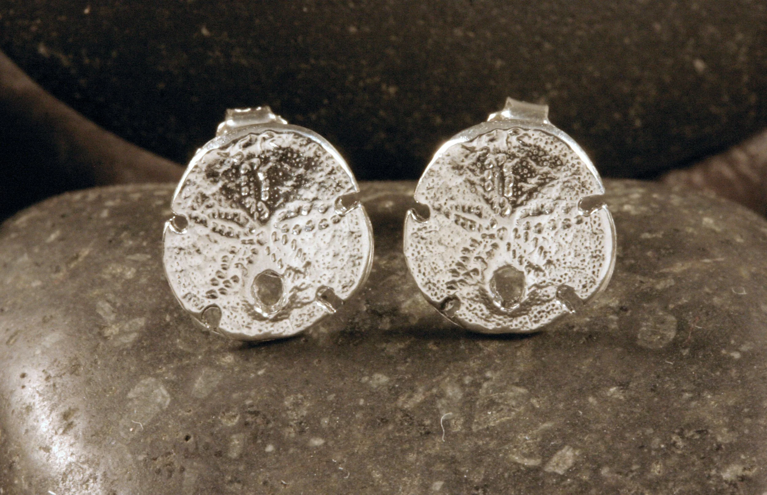A front view of sterling silver mini sanddollar stud earrings.