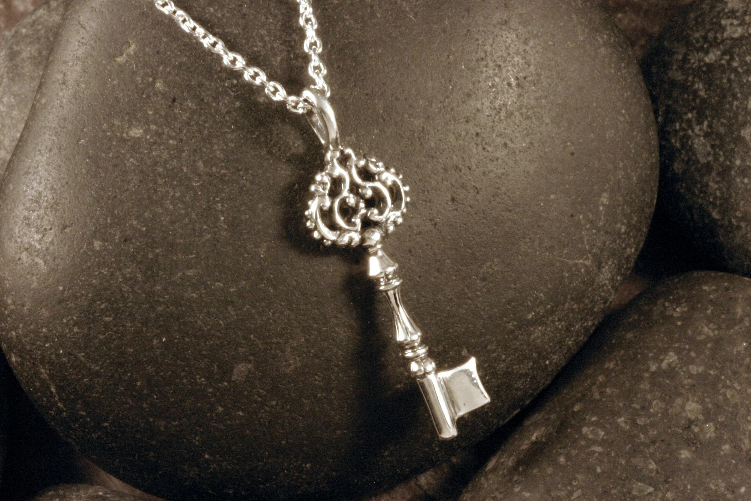 An oxidized sterling silver key charm designed after antique style keys.