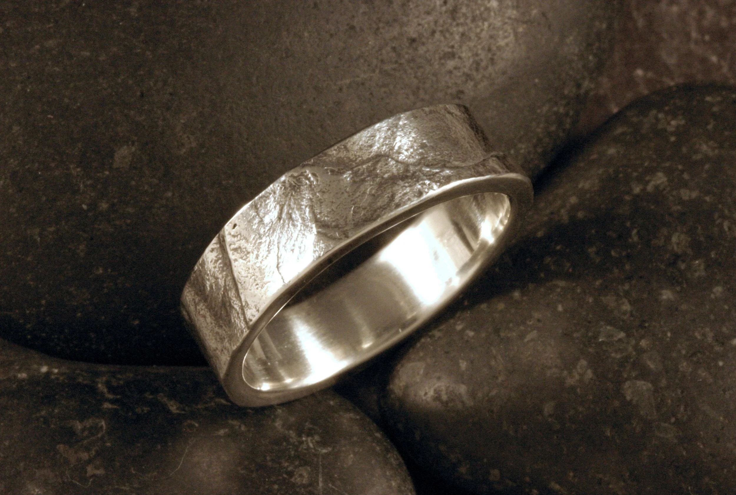 An oxidized sterling silver flat band with a slate stone texture.