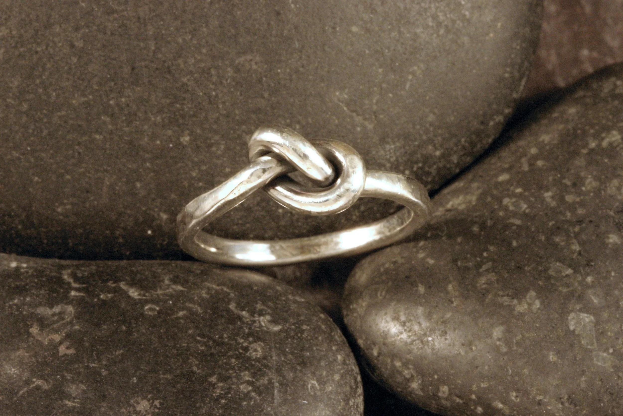 An oxidized sterling silver knot ring with hammered textured sides.