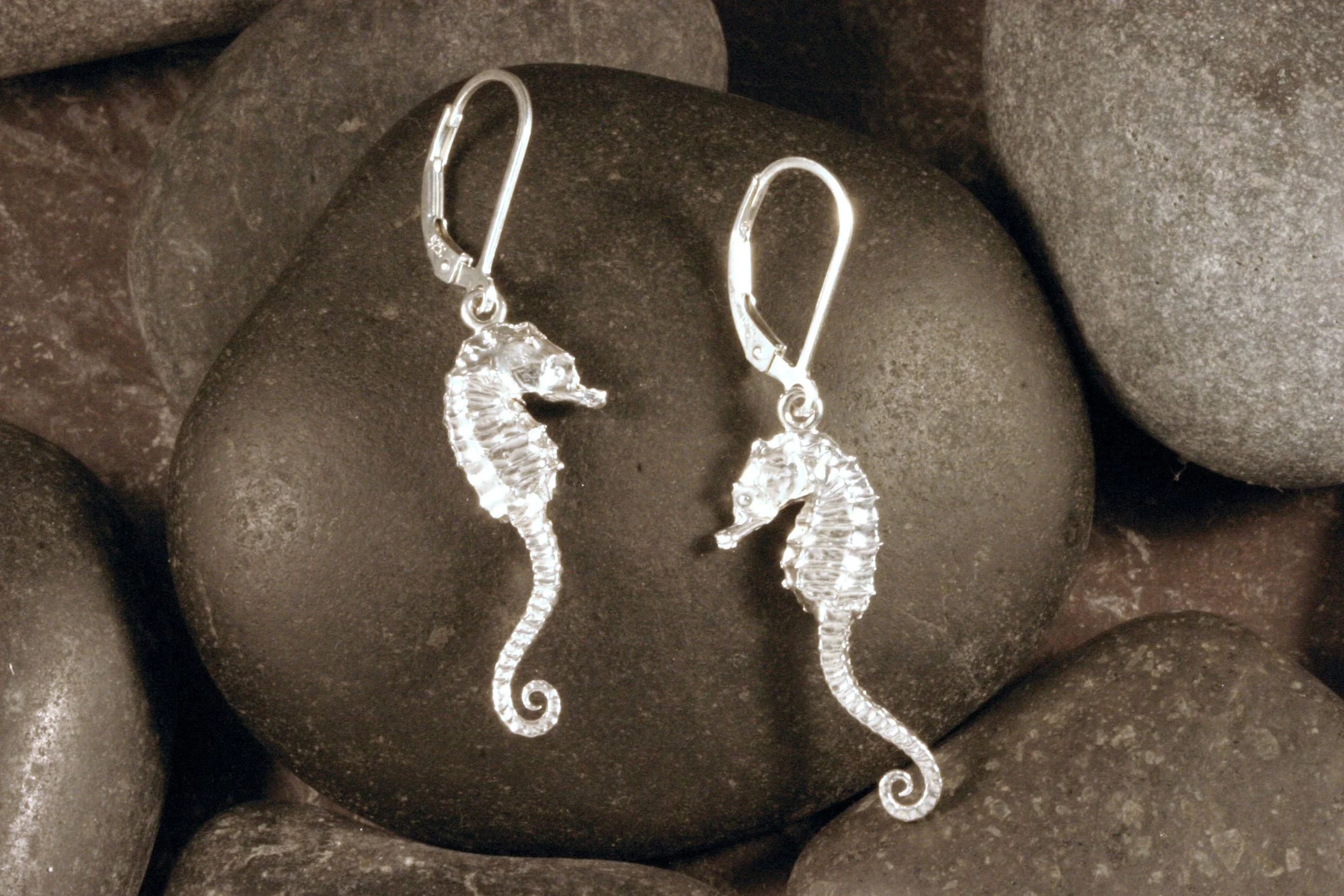 Shiny sterling silver seahorse earrings with long tails on leverback ear wires.