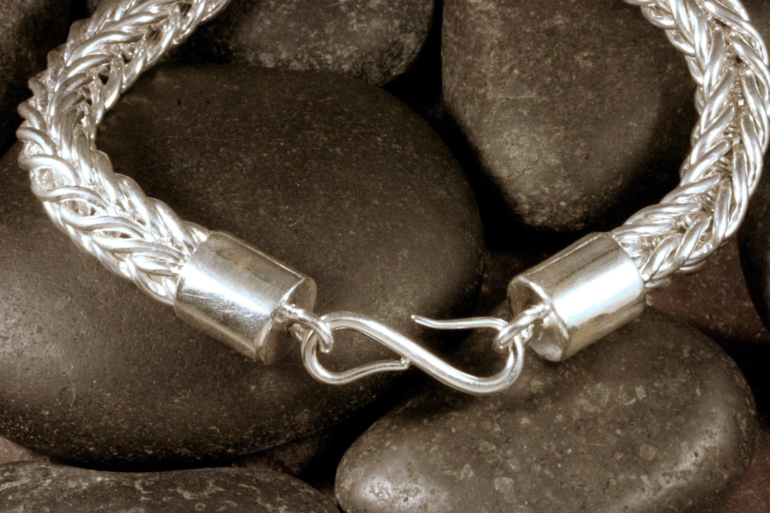 A close up of the S hook clasp and smooth end caps in a heavy sterling silver double loop in loop chain bracelet.
