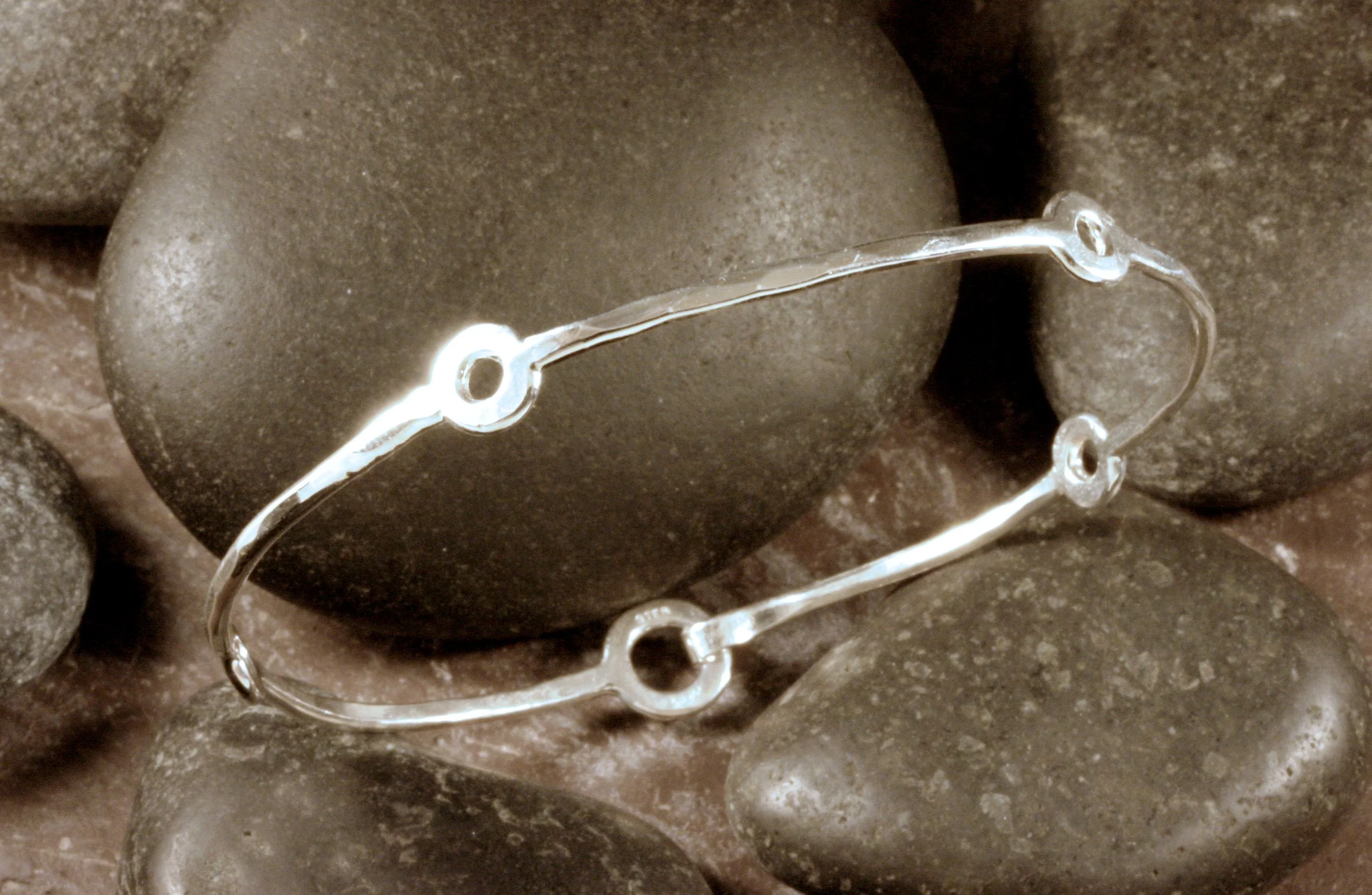 A sterling silver fitted bangle bracelet with 4 stations and a loop and hook clasp.