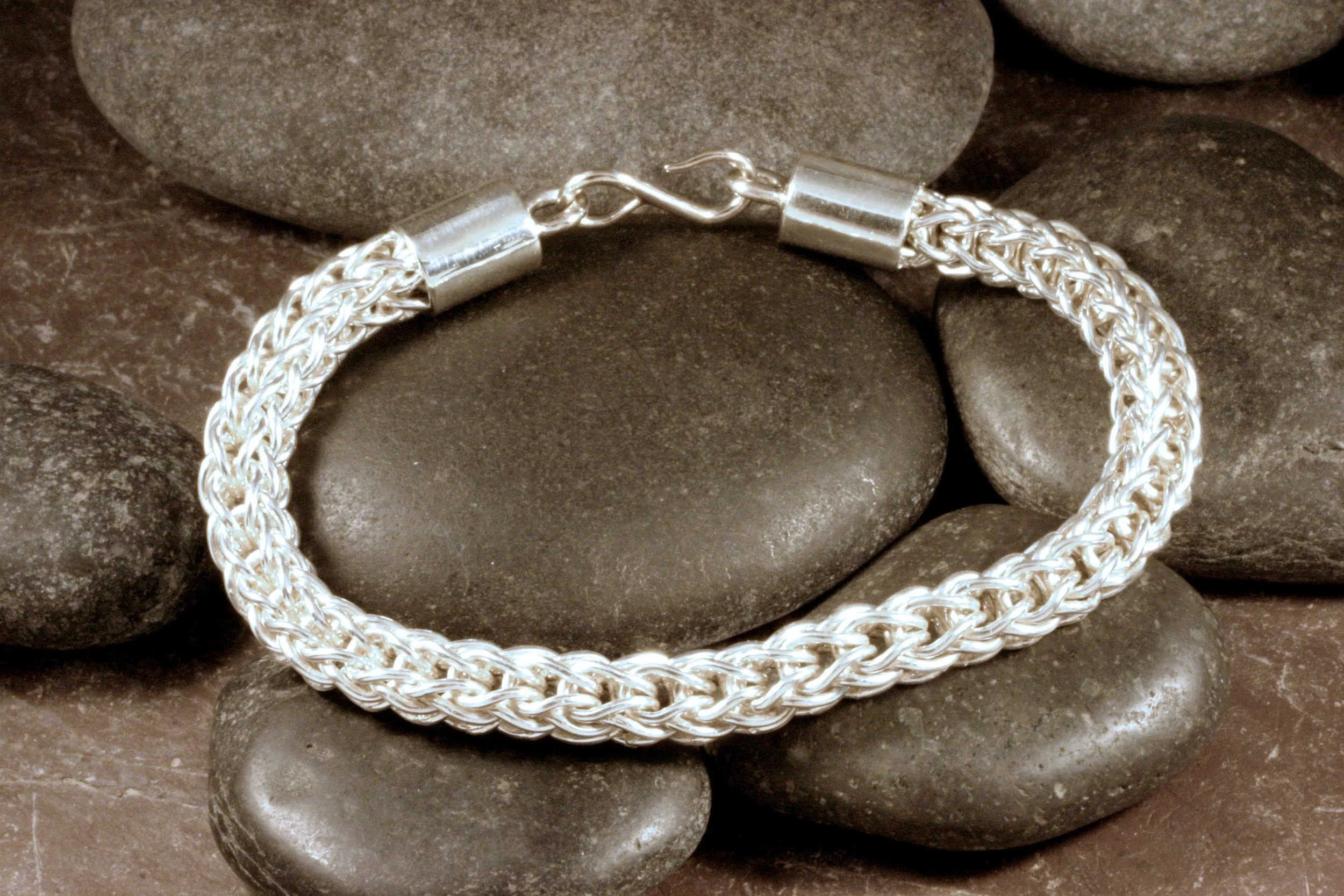 A handwoven sterling silver 2 way loop in loop chain bracelet with smooth end caps and an S hook clasp.