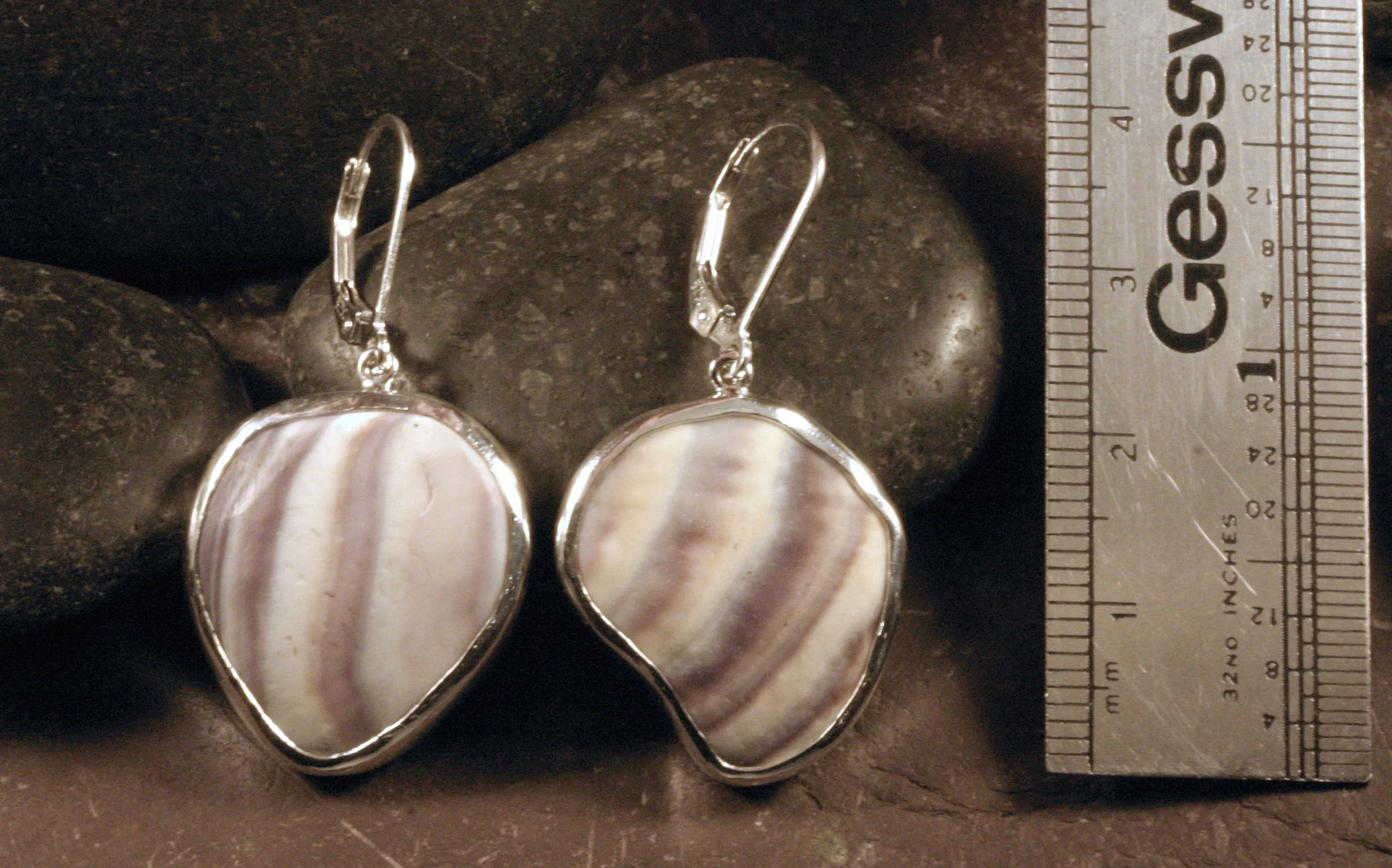 Sterling silver bezel set round pear shaped wampum earrings next to a ruler.