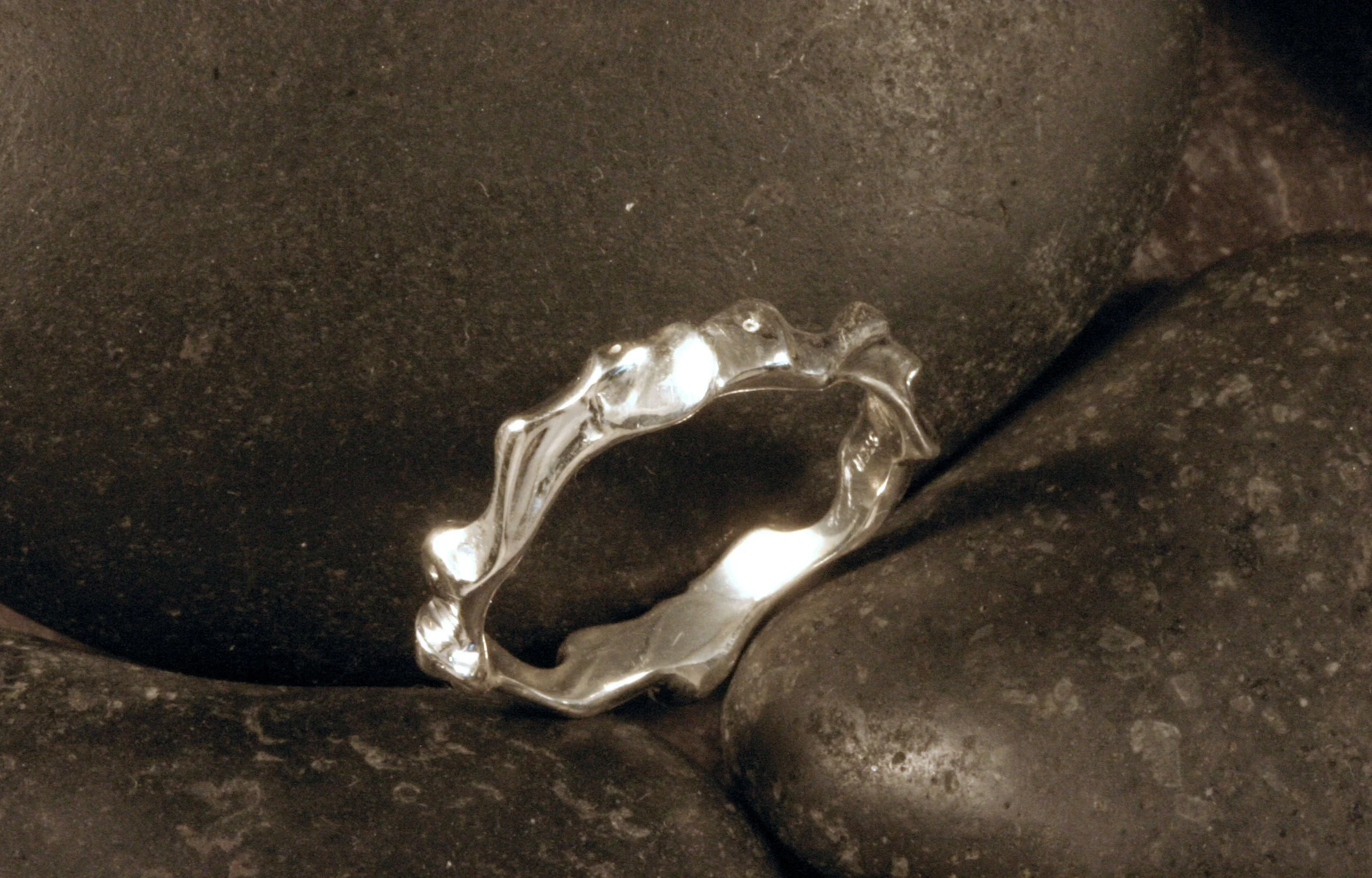 A three quarter view of a sterling silver funky ring with a continuous pattern.