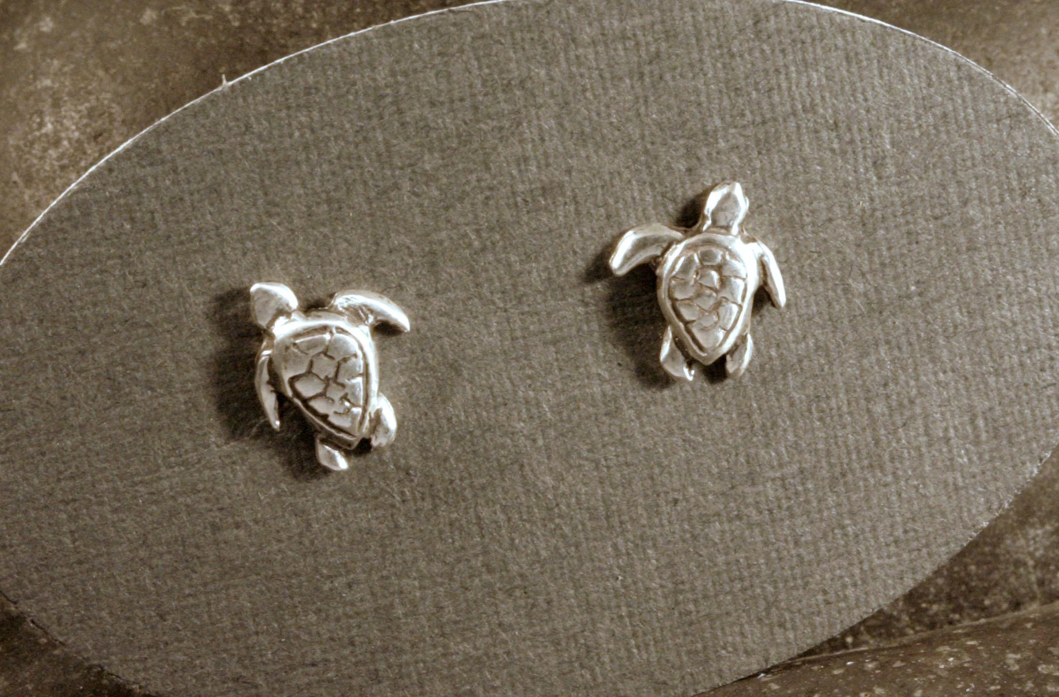 Oxidized sterling silver mini turtle stud earrings on a gray display card.