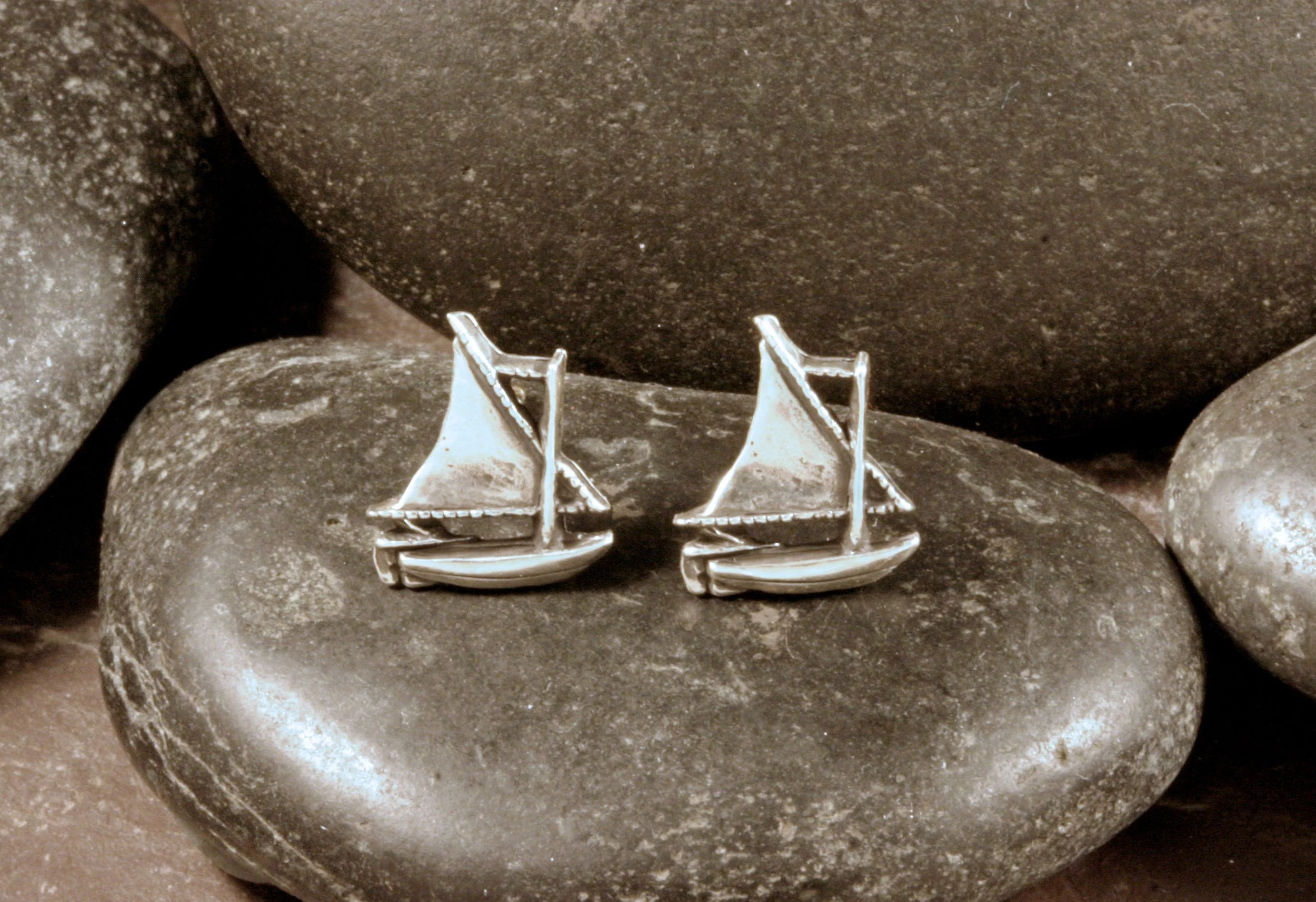 Oxidized sterling silver sailboat stud earrings in a front view.