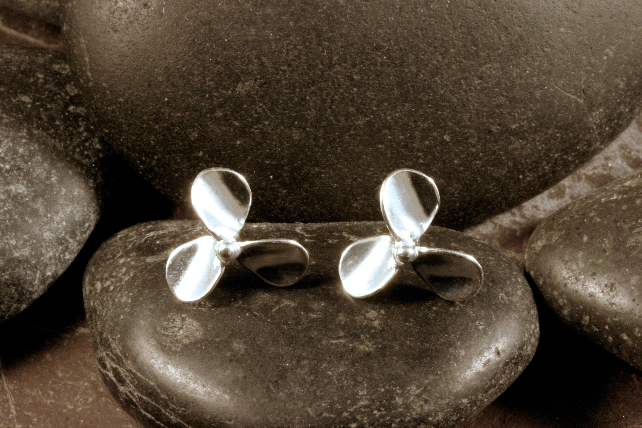 A front view of medium sized sterling silver 3 blade propeller stud earrings.